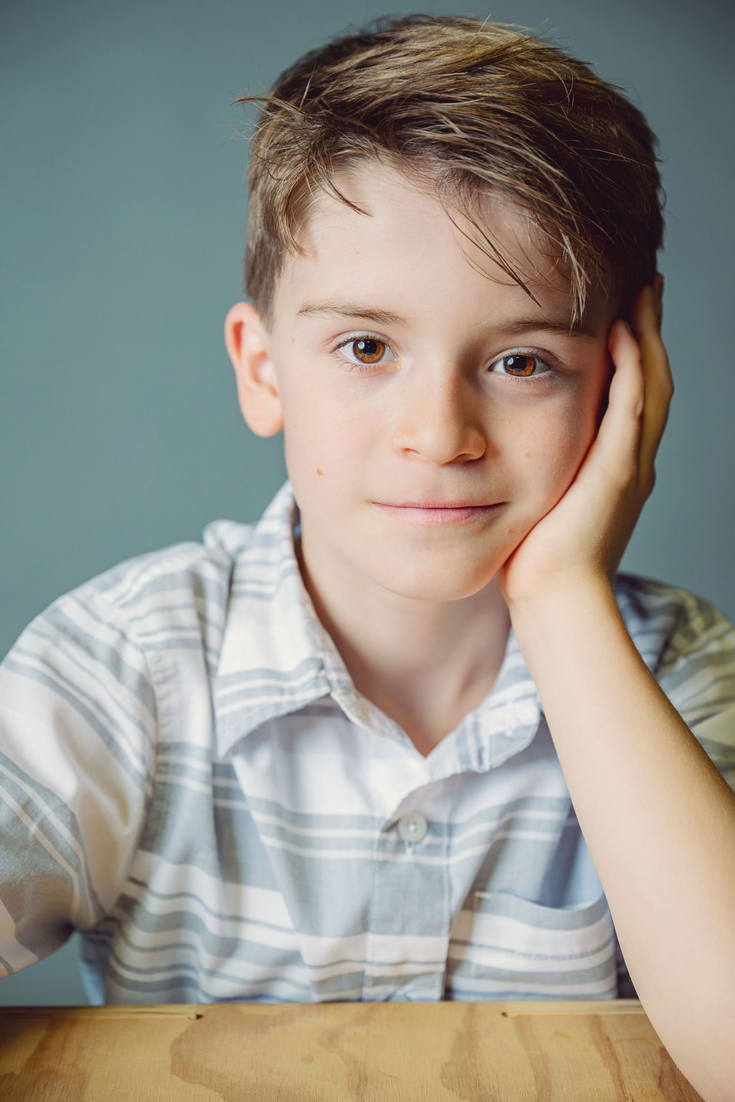 A series of four similar portraits showing someone in a white striped shirt resting their head on their hand.