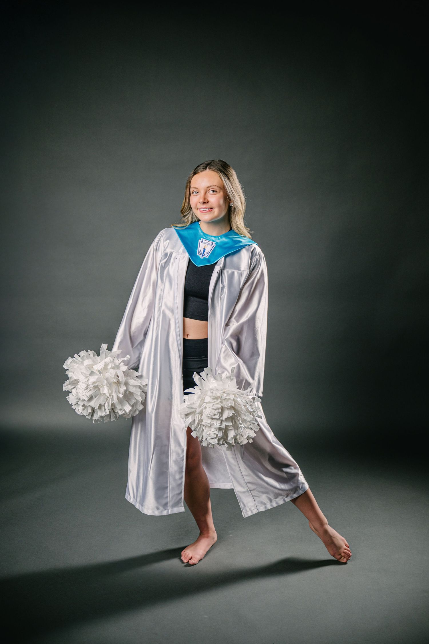 A dancer in a white button-up shirt performs dynamic movements against a dark studio backdrop.