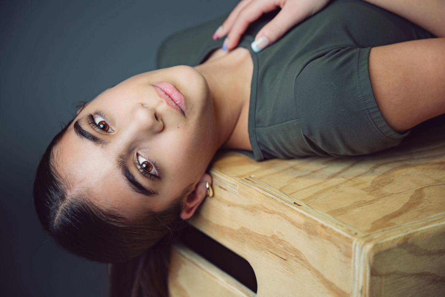 Person lying on wooden floor with dark lipstick and dramatic lighting creates artistic portrait series.