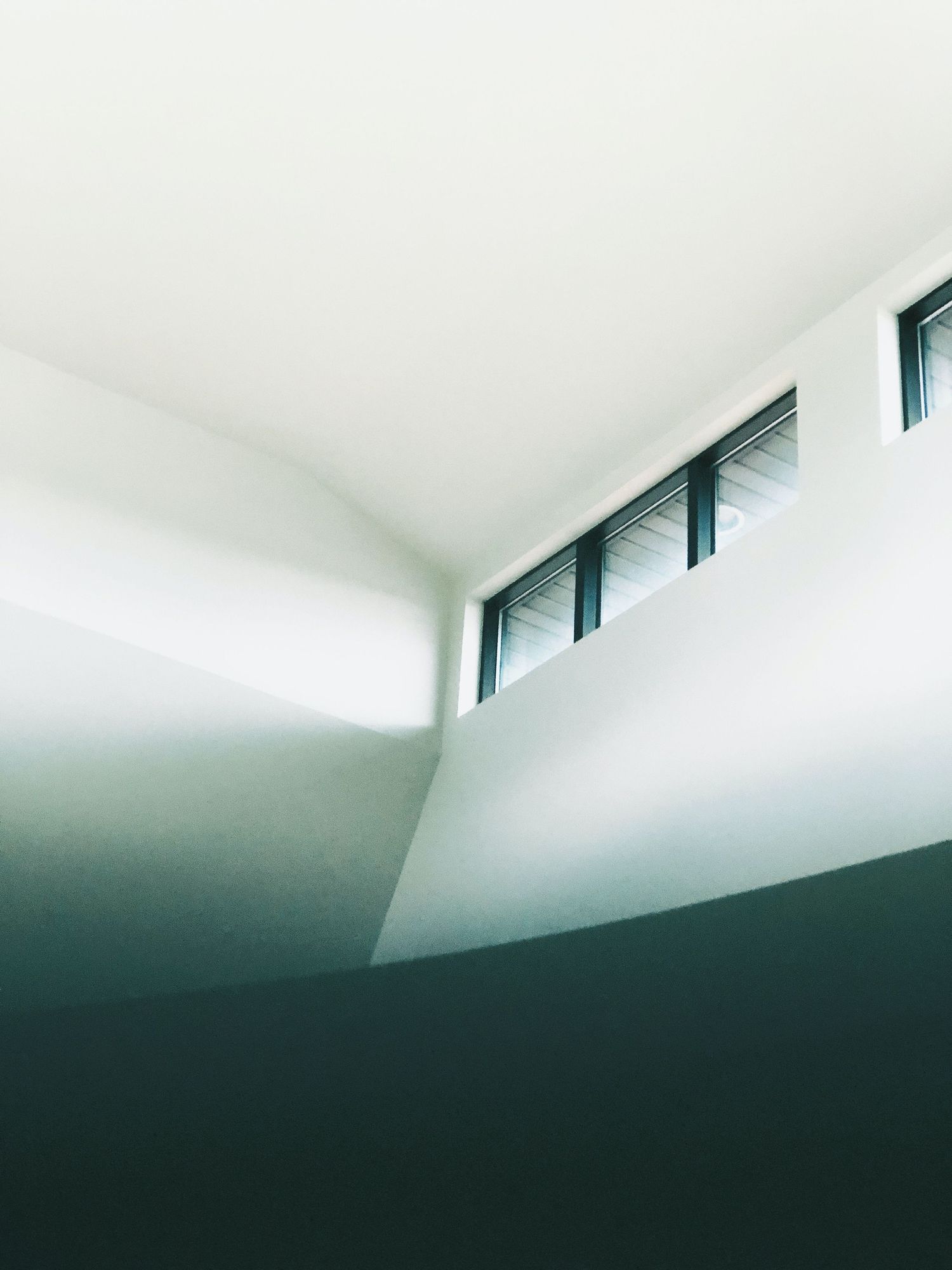 Minimalist architectural detail showing a gradient of white ceiling meeting dark walls in a modern interior space.