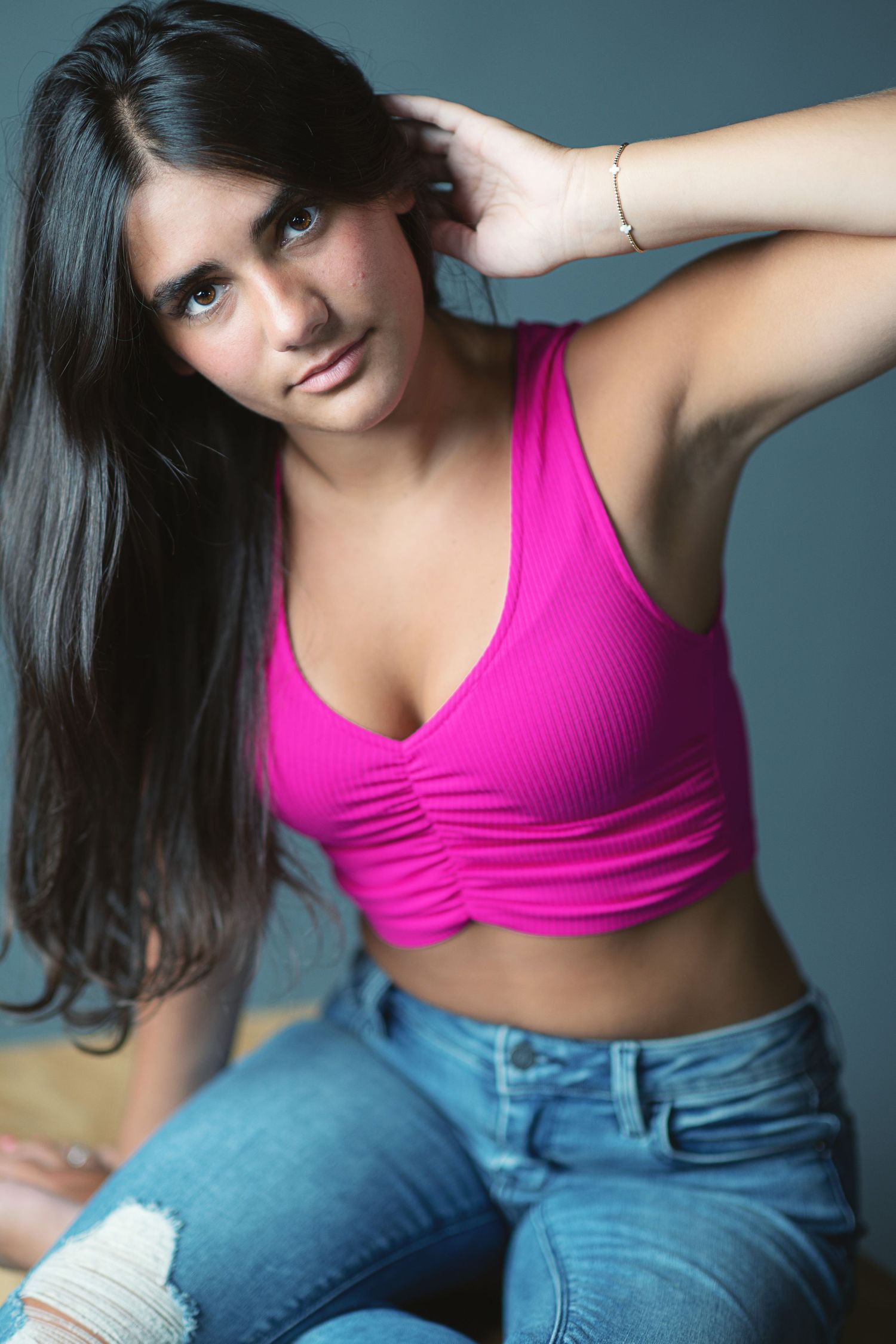 Person wearing hot pink sports bra and blue jeans poses in multiple casual positions against neutral background.