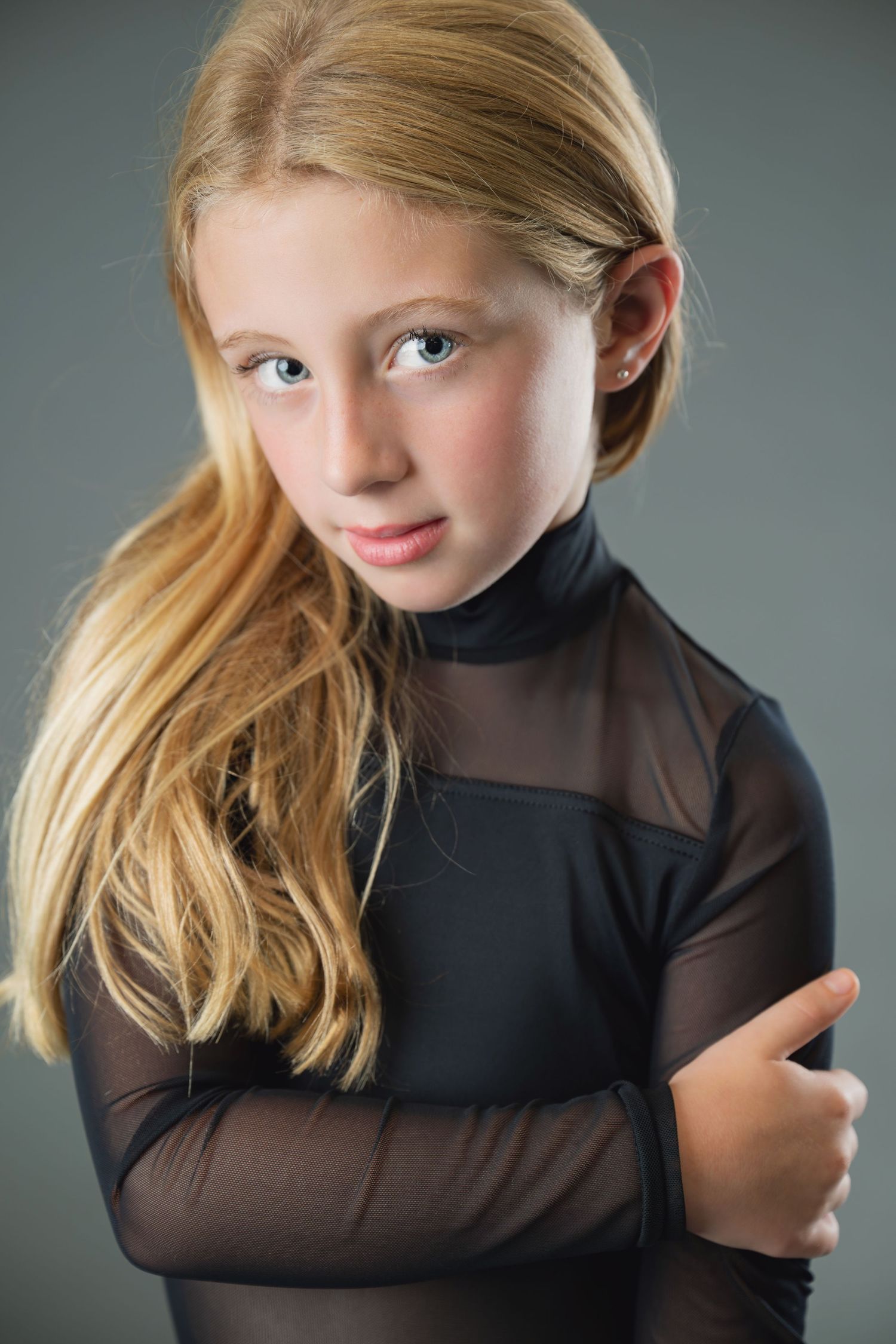 A series of portrait photos showing someone in a black sheer top posing playfully against a gray backdrop.