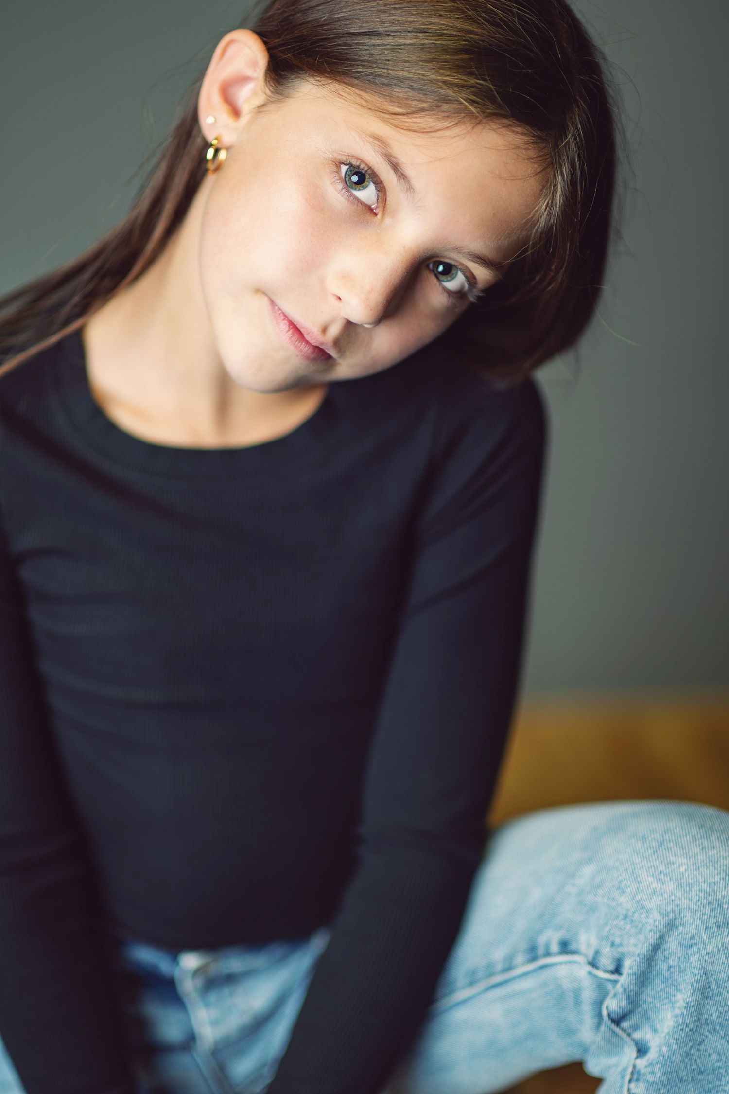 Artistic portrait series showing different angles and poses in a black top against a gray background.