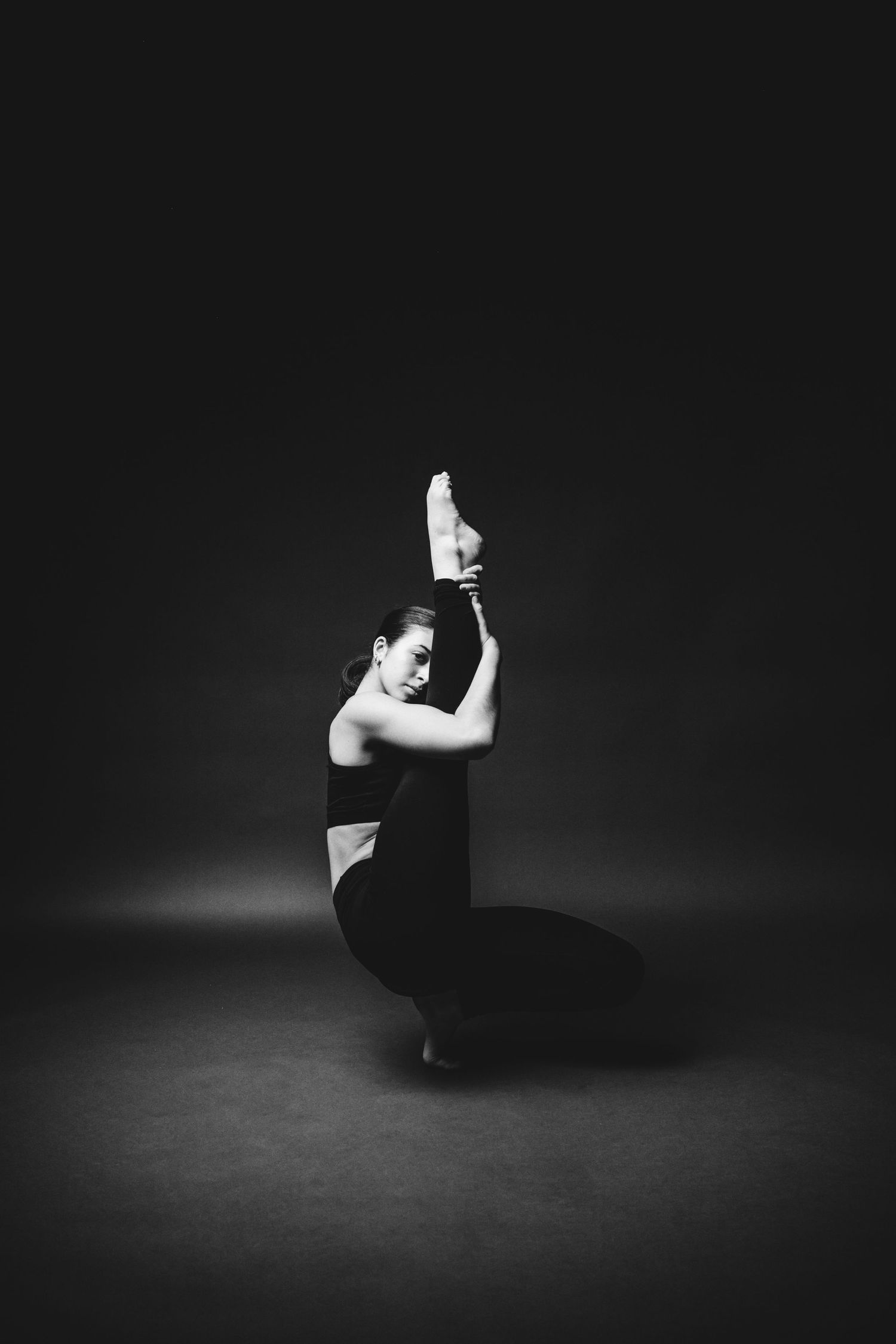 Dramatic black and white sequence of a dancer performing fluid movements in a dark studio space.