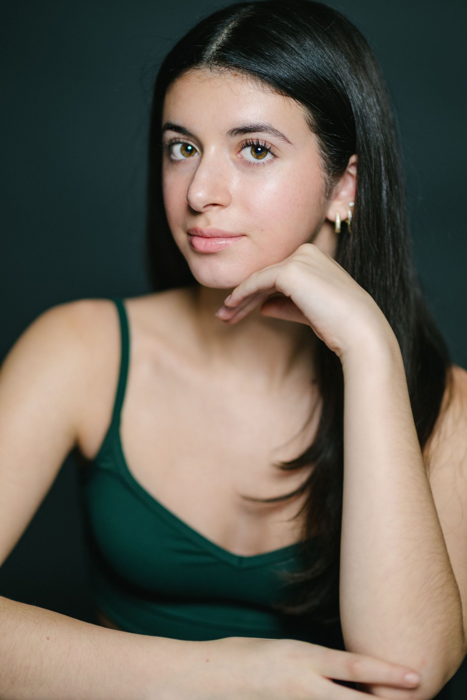 A series of portrait photos showing someone with dark hair wearing a black tank top against a dark background.