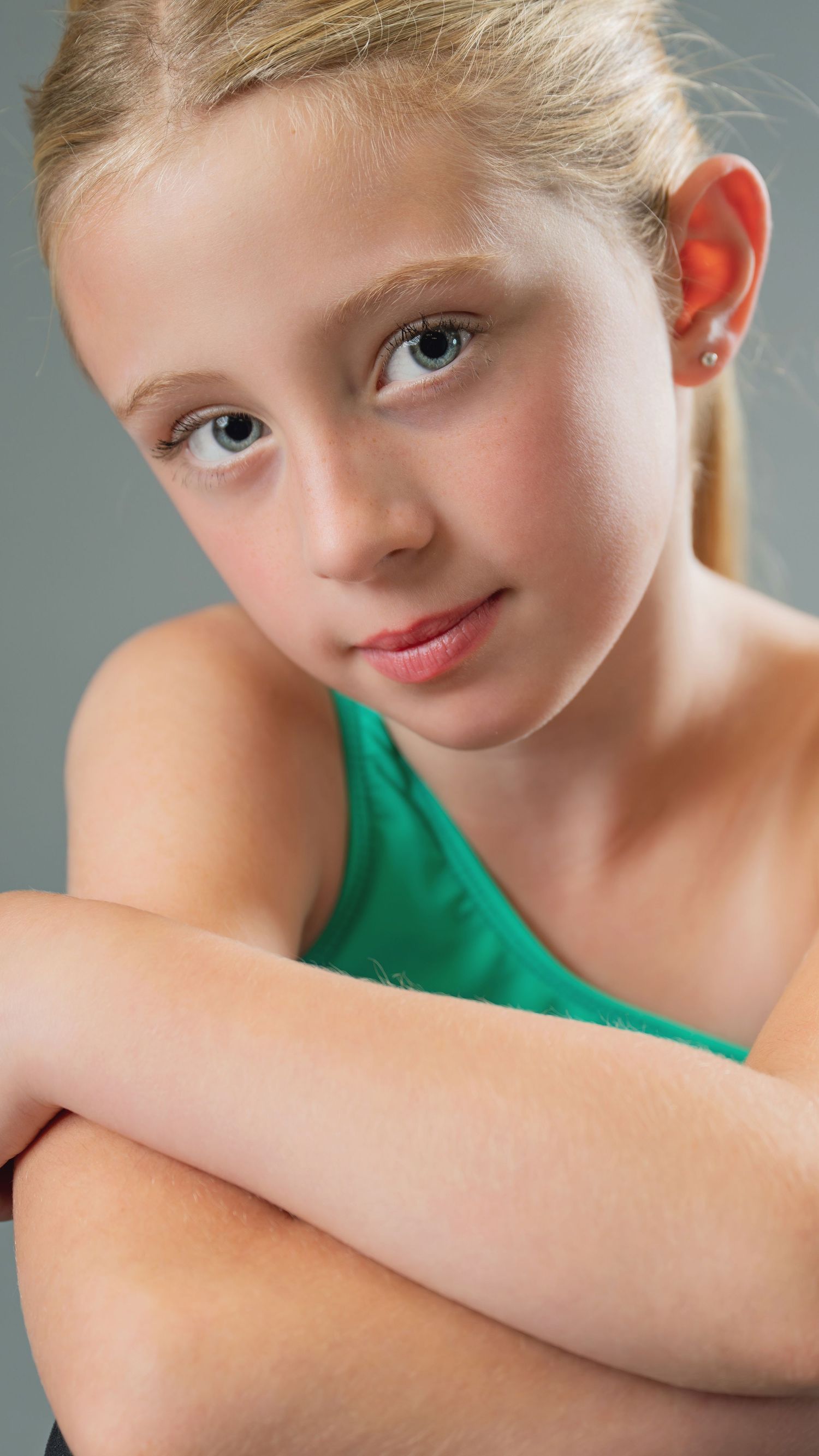 A sequence of close-up portrait shots showing different expressions and angles in a green top against a gray background.