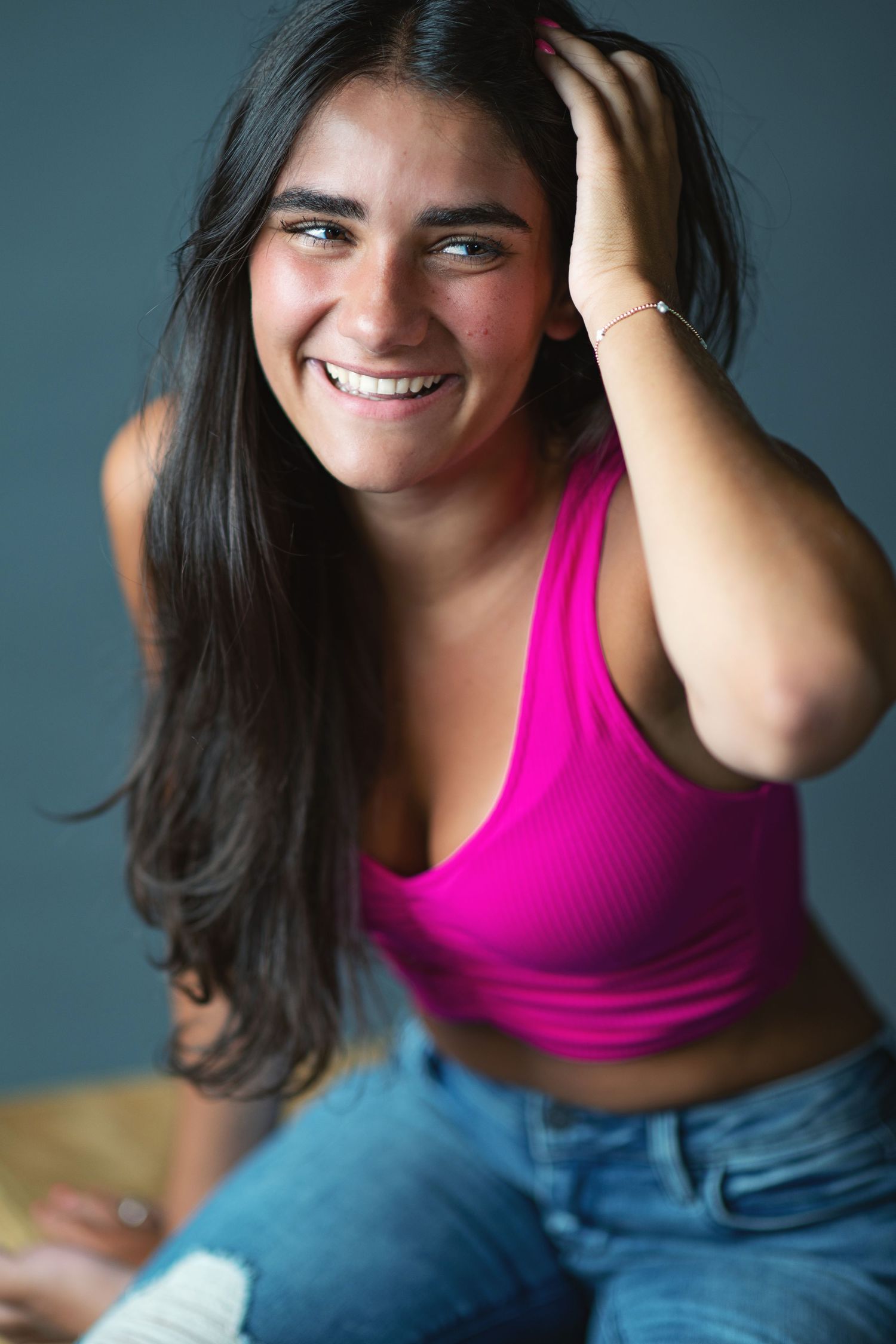 A series of expressive portrait shots showing someone in a bright pink tank top and jeans against a dark background.