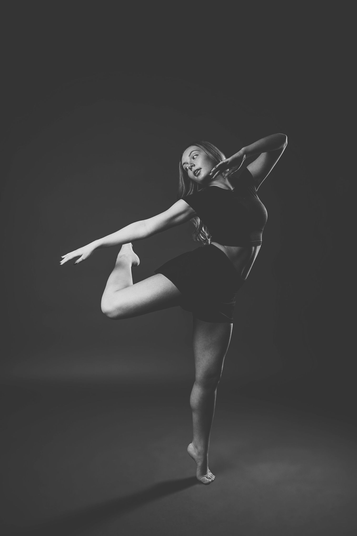 Black and white photo series of a dancer performing graceful movements in a dark studio setting.