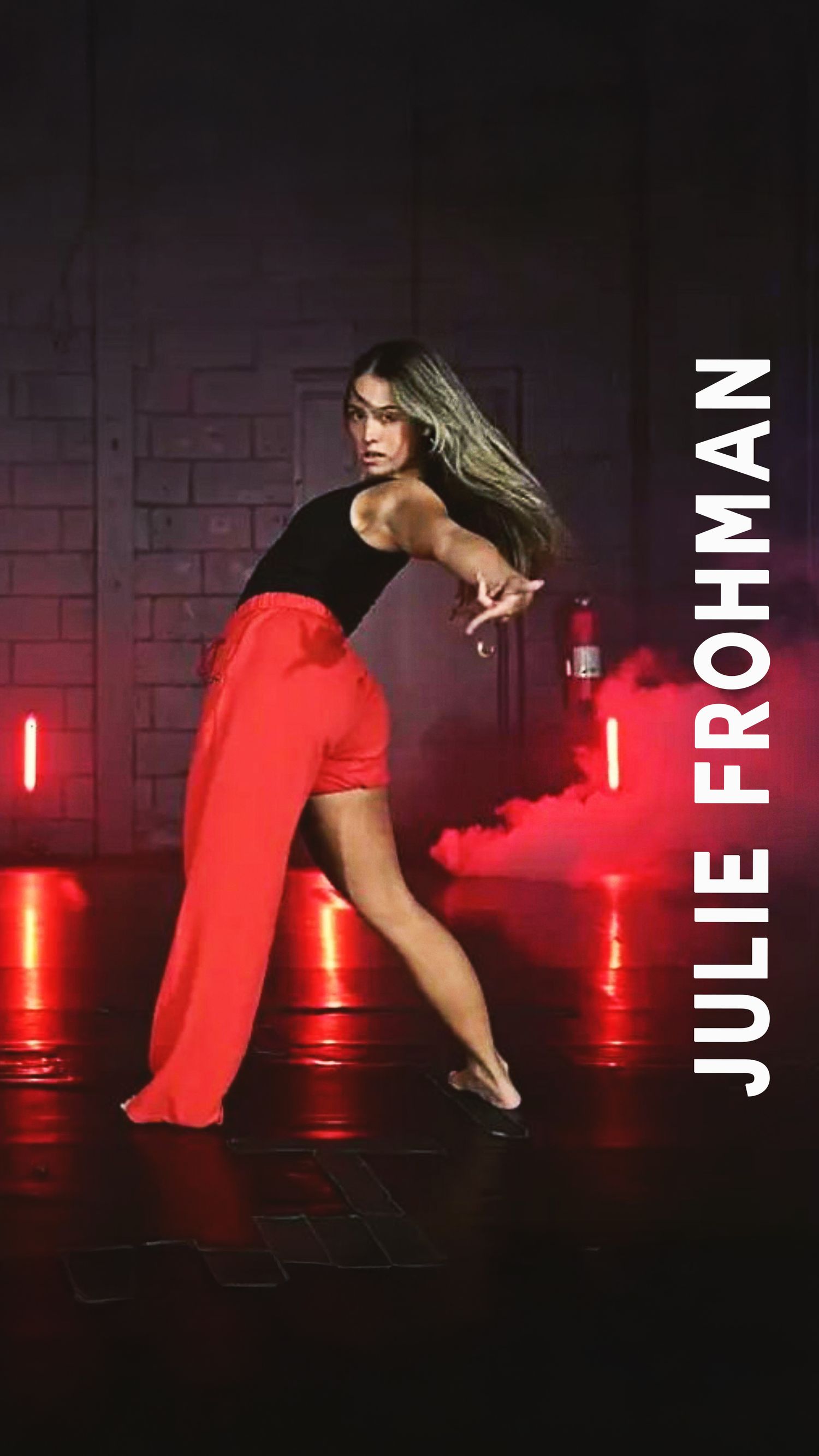 A dancer in a red dress performs a dynamic contemporary dance sequence against a dark backdrop with red lighting.