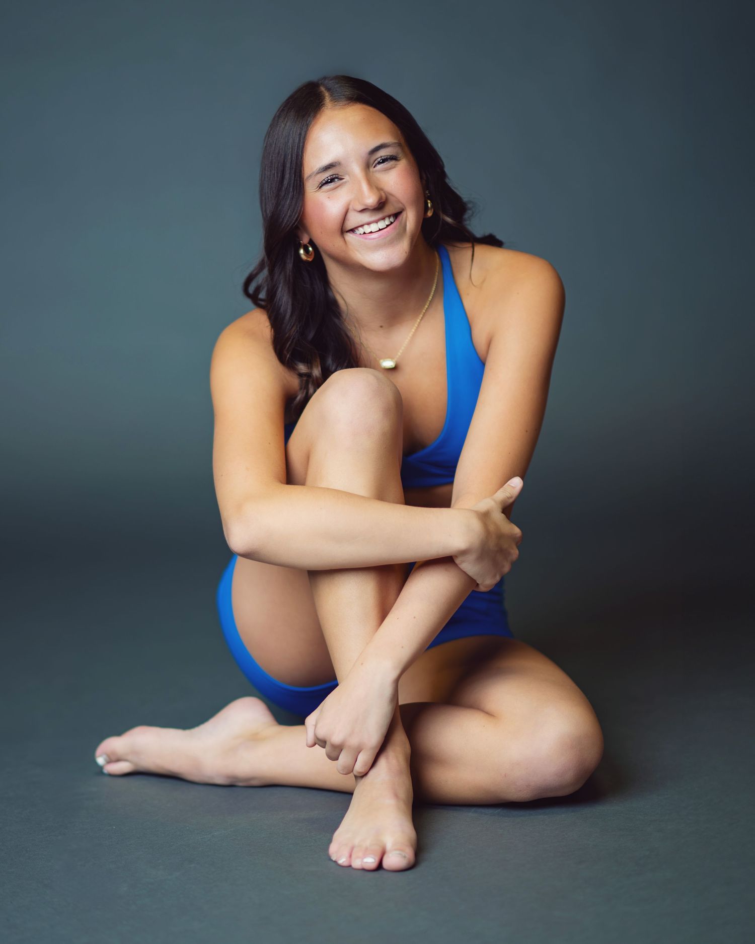 A figure in a blue leotard poses gracefully on a gray studio floor in a series of artistic dance positions.