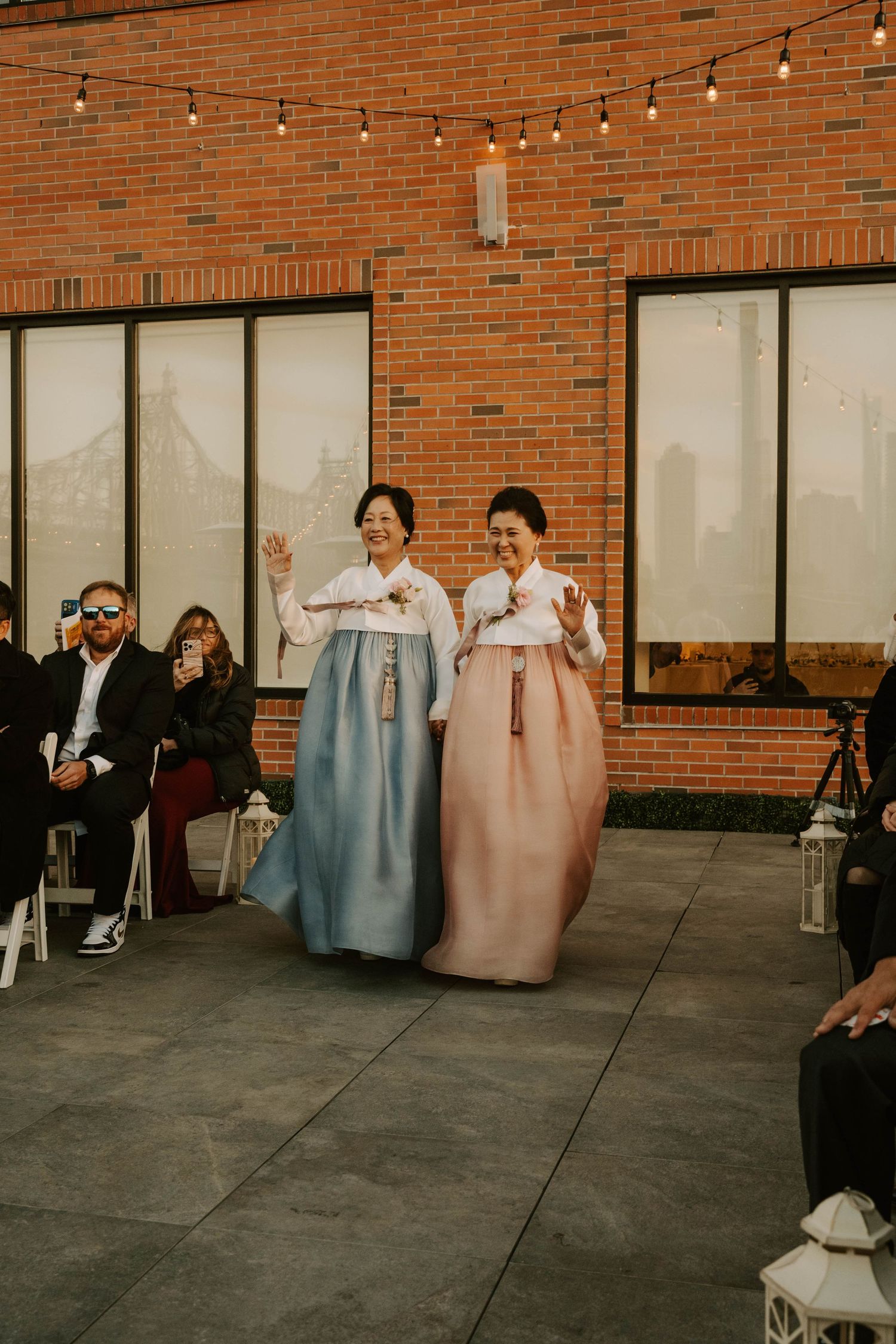 String lights illuminate an outdoor brick venue space with a casual gathering setup.