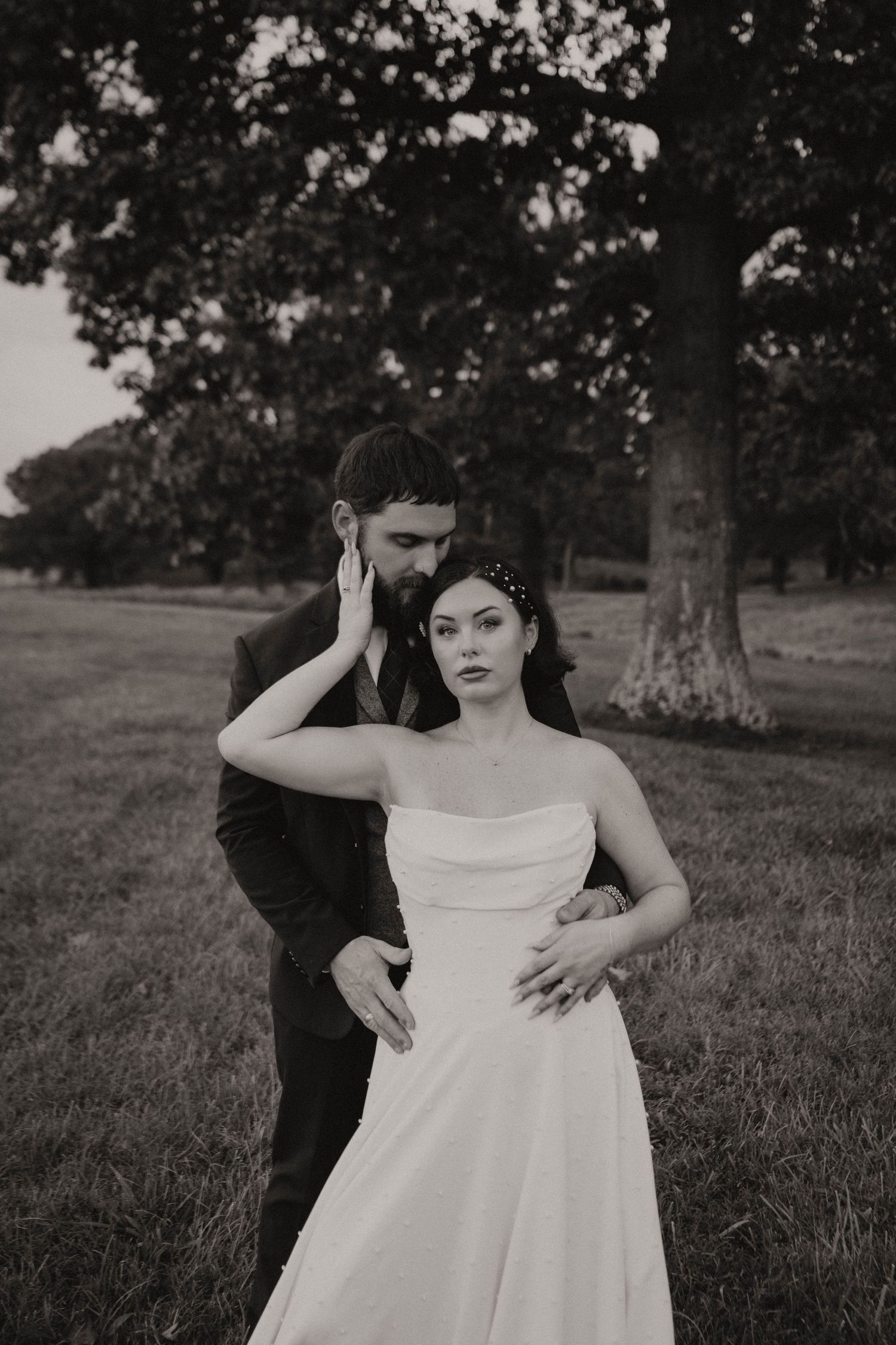 Black and white photo series of a couple in romantic poses outdoors with woman in white dress and man in dark attire.