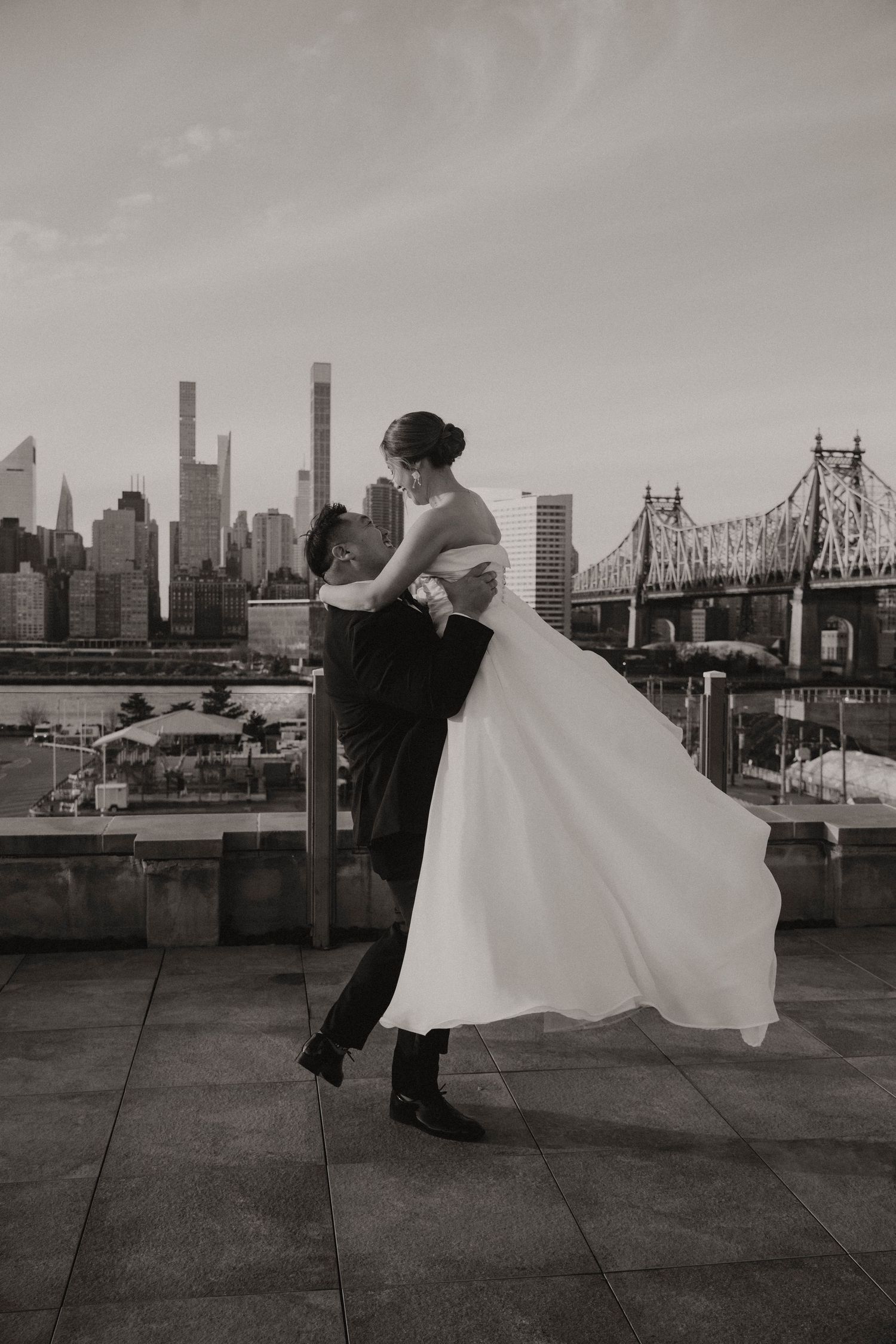 Couple poses against NYC skyline in formal black and white attire.