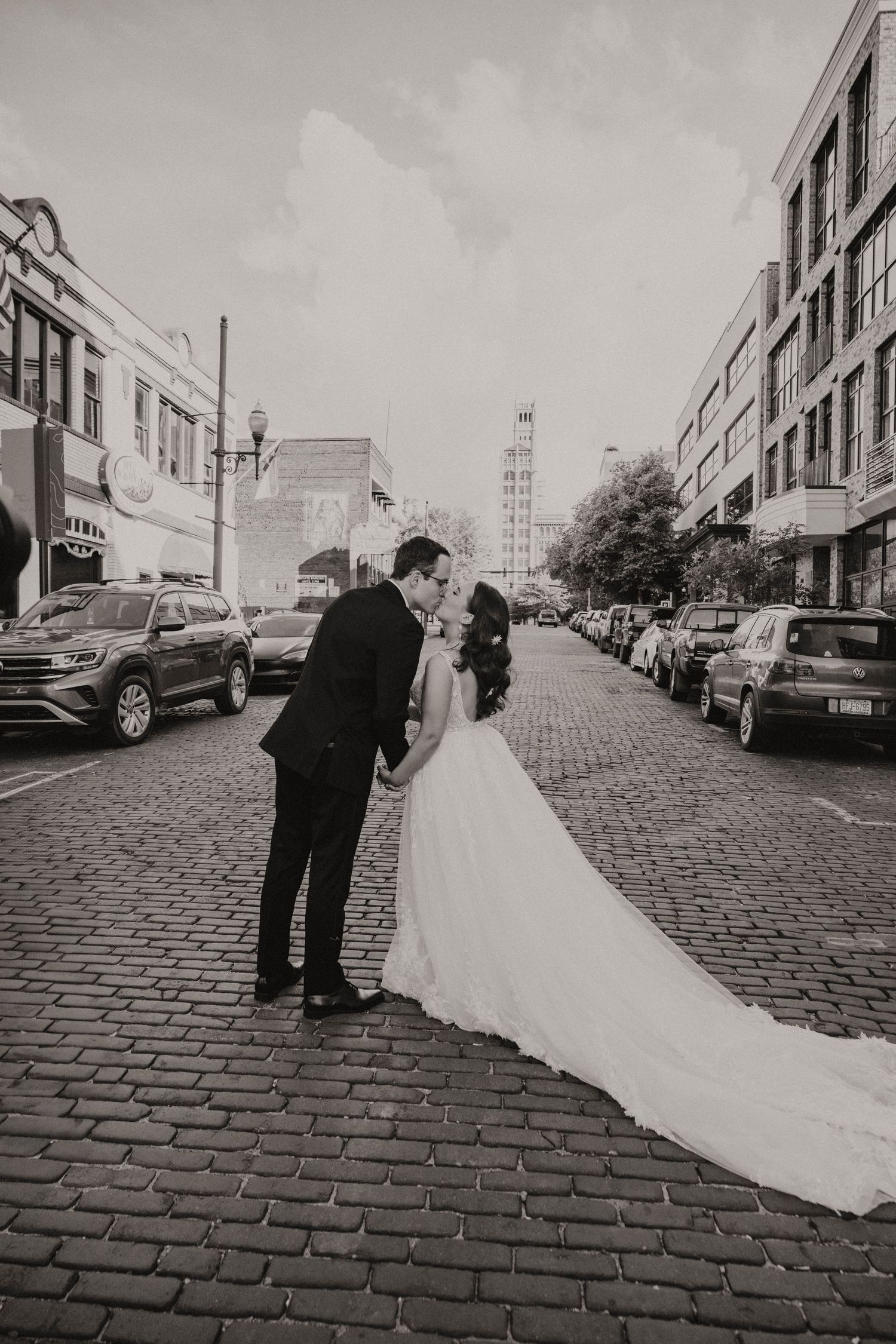 A black and white wedding photo series showing a couple on a cobblestone street with historic buildings in the background.