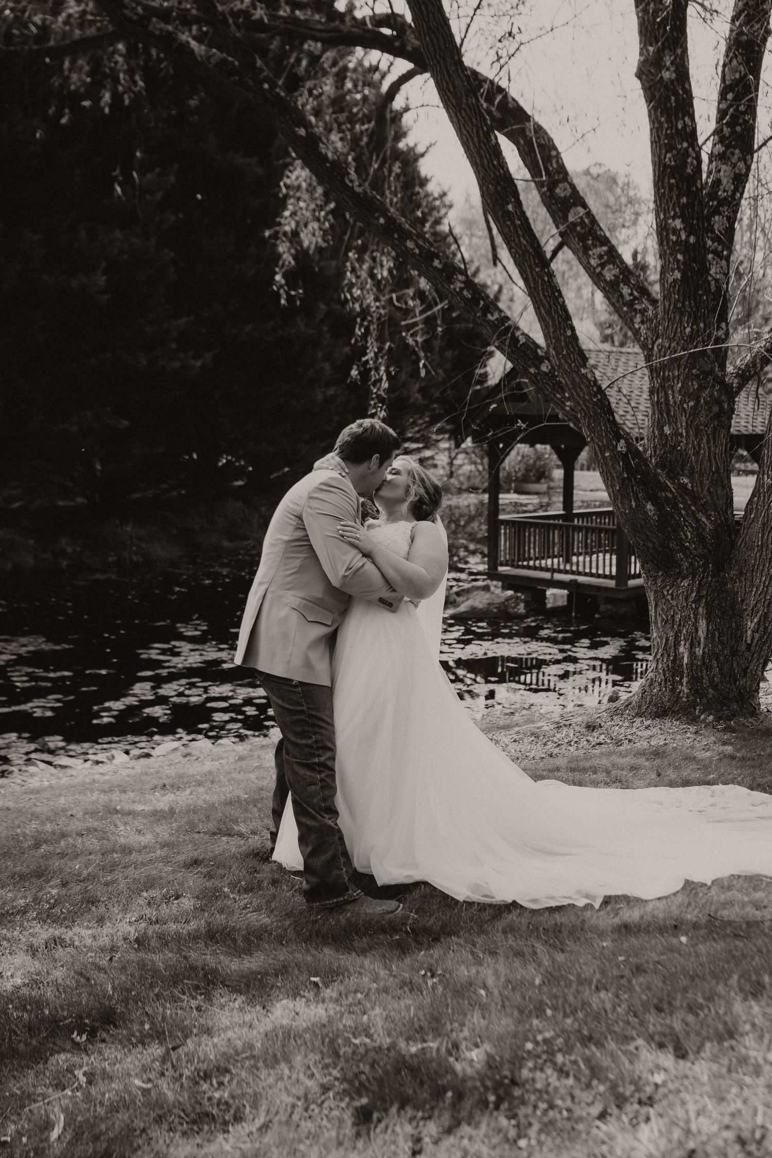 A romantic black and white wedding photo series showing a couple sitting together under trees in a garden setting.