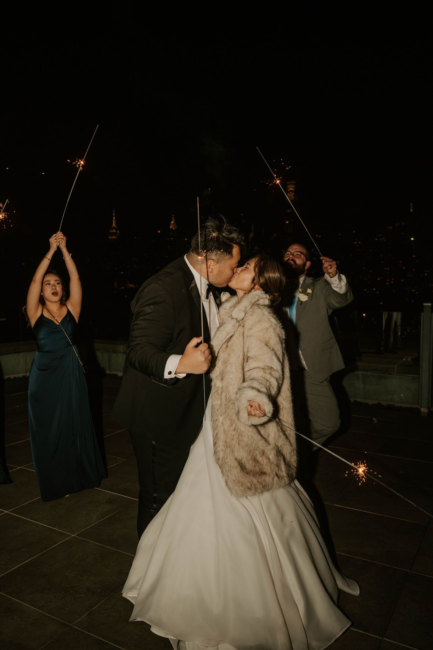 Wedding guests celebrate on a dark dance floor with sparklers creating a magical nighttime atmosphere.
