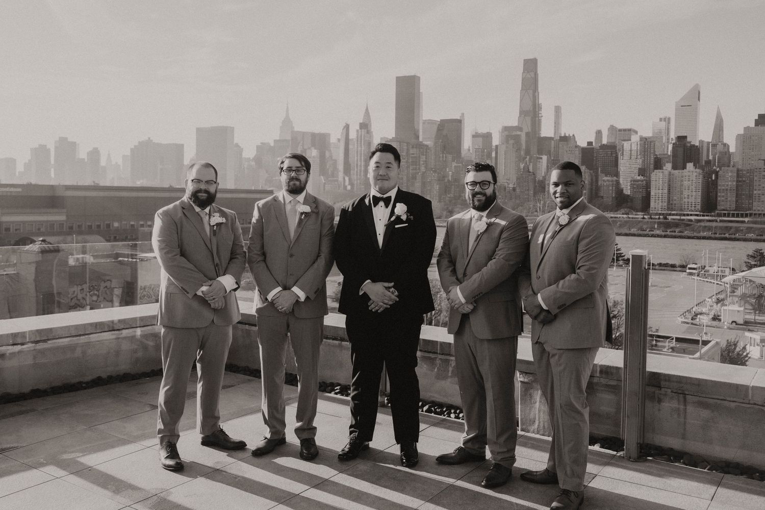 A group stands on a rooftop overlooking the New York City skyline in a black and white vintage photograph.
