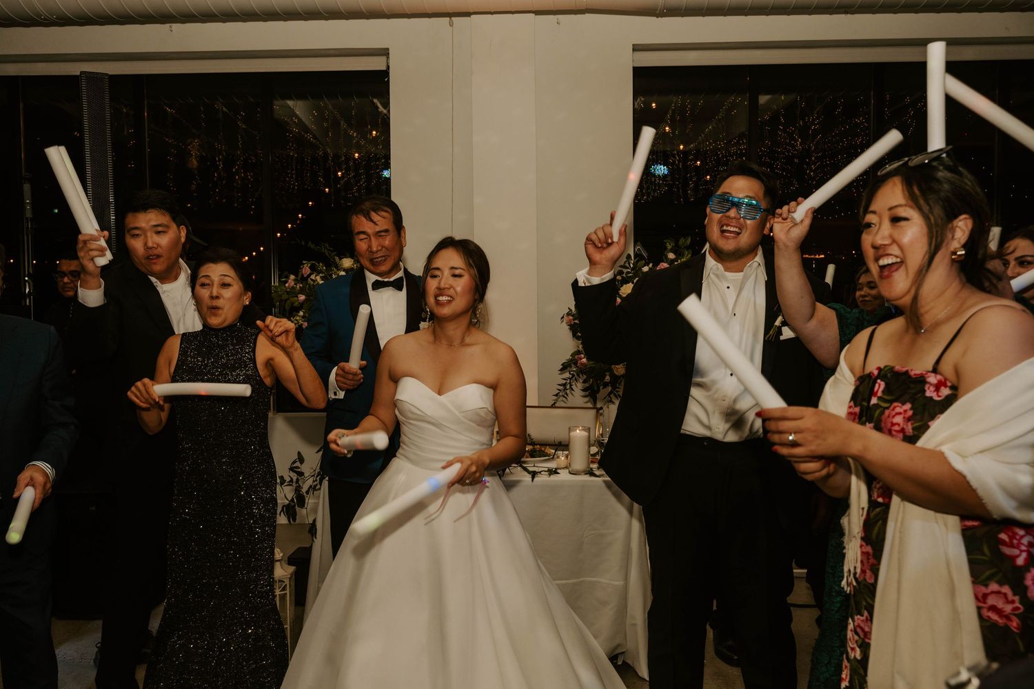 Wedding guests dance and celebrate during a lively reception party at an indoor venue.