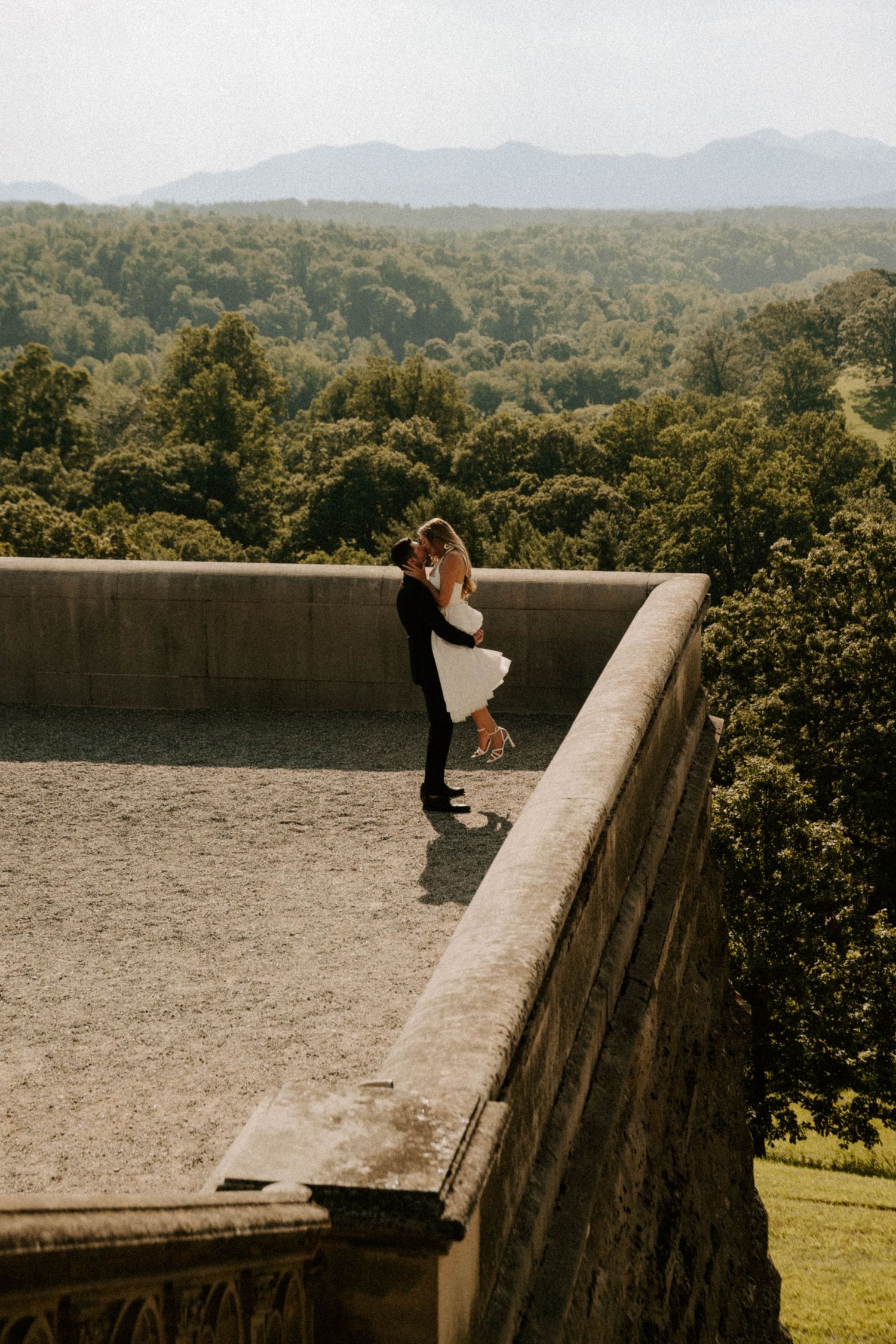 Scenic panoramic sequence of a stone wall overlooking rolling green hills and mountains in the distance on a sunny day.