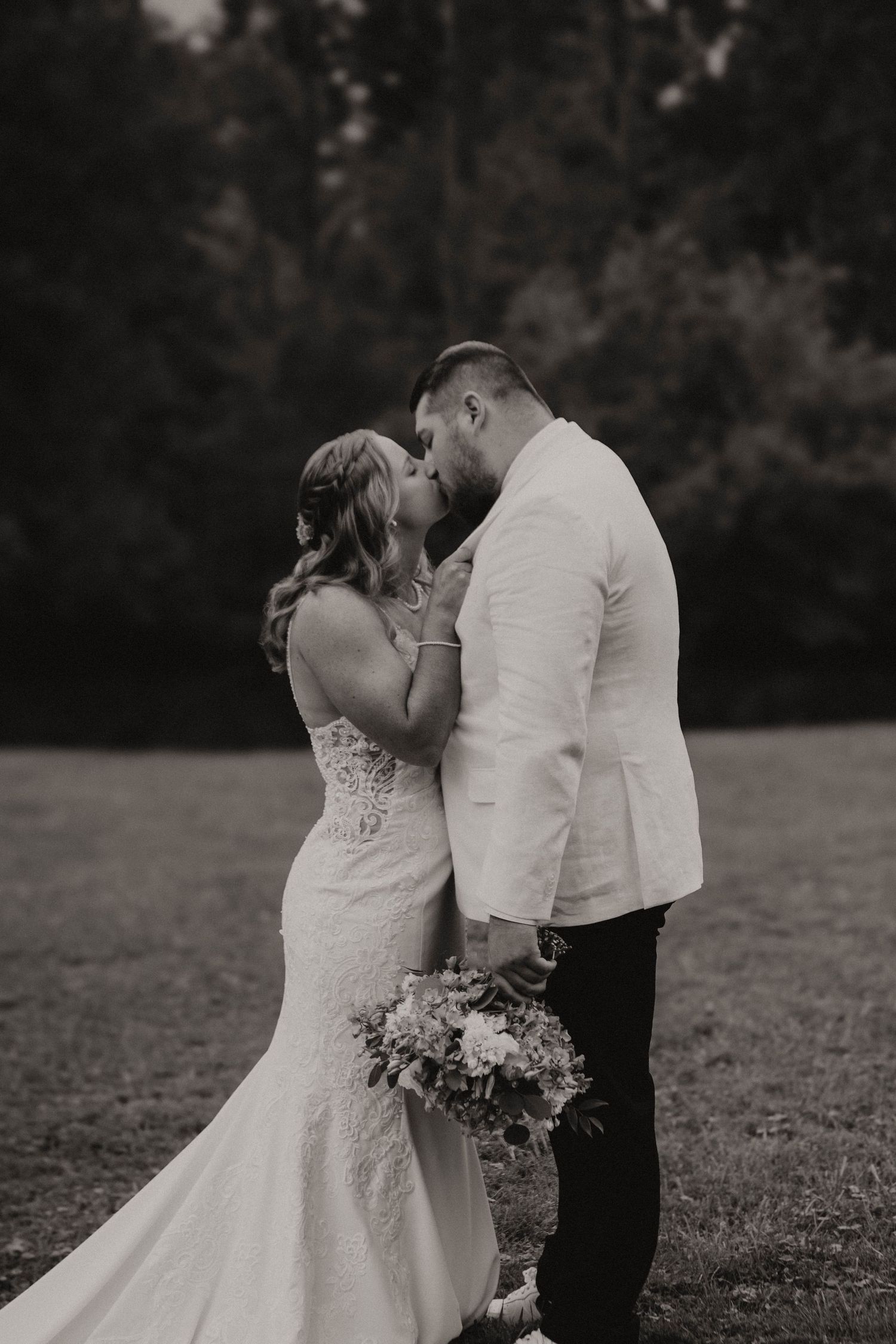 A romantic black and white wedding photo series showing a couple sharing intimate moments in an outdoor setting.