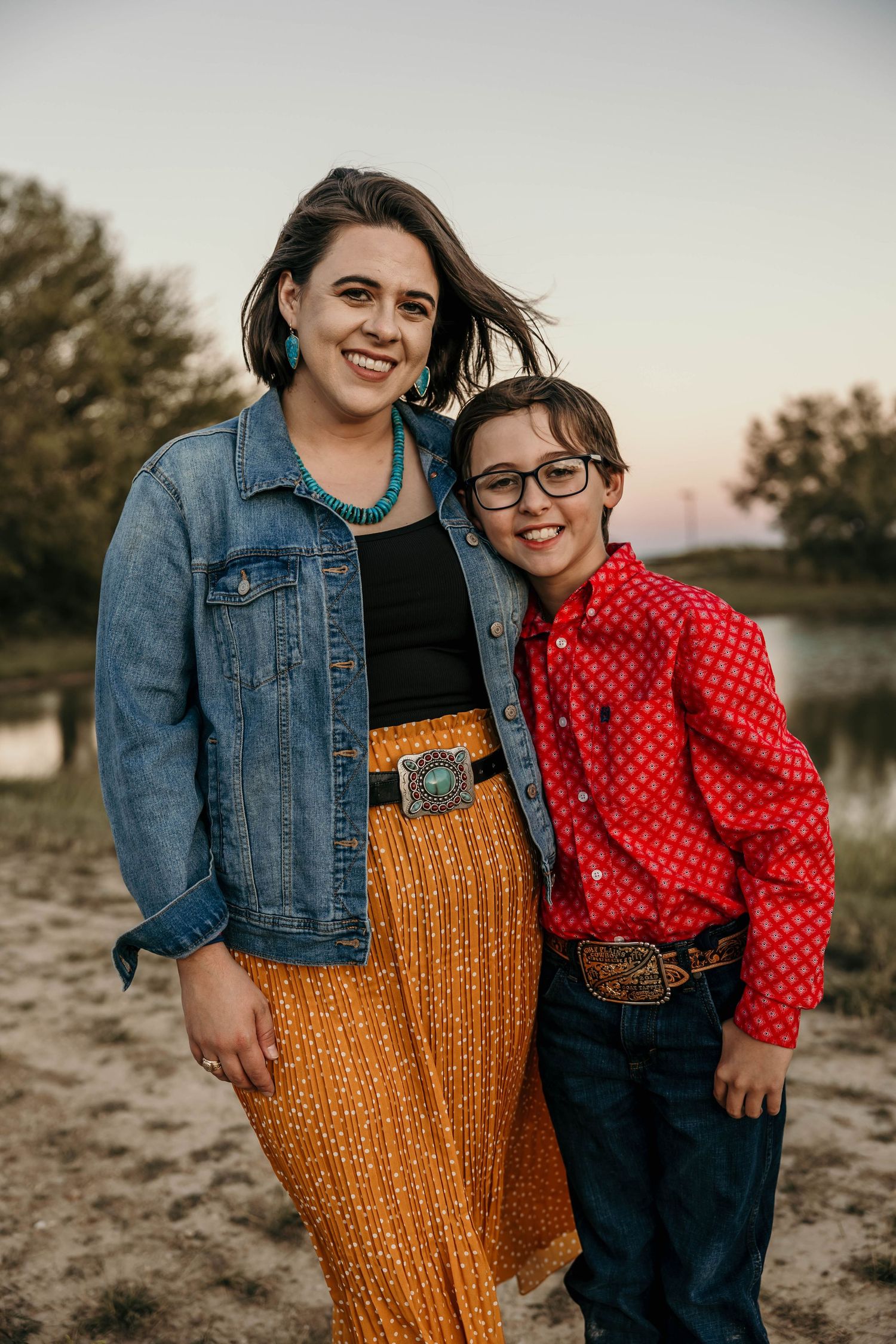 Two people in casual western attire posing outdoors with denim and a mustard yellow skirt.
