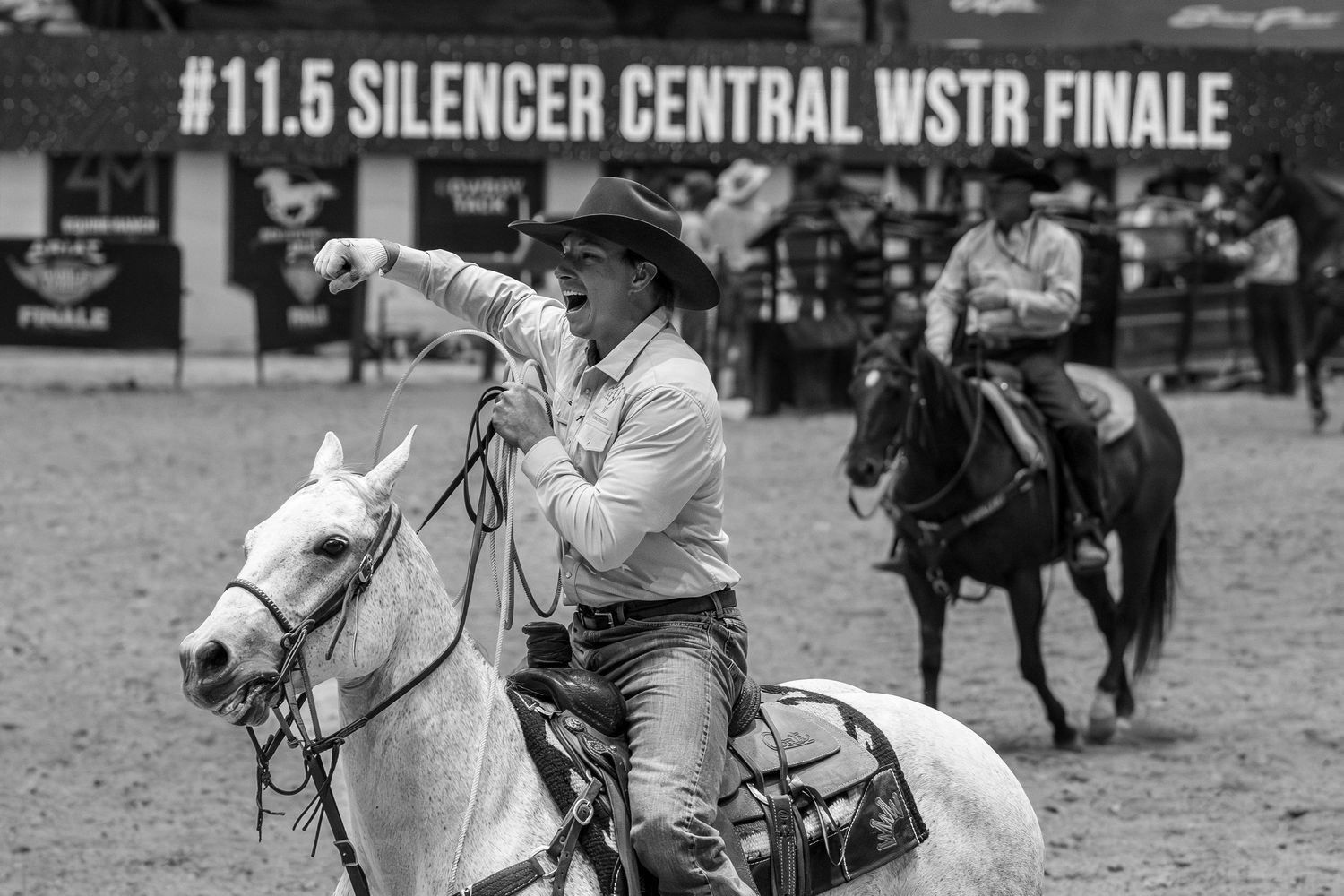 Cowboy on white horse competing at Silencer Central WSTR Finale rodeo event, black and white action photo.