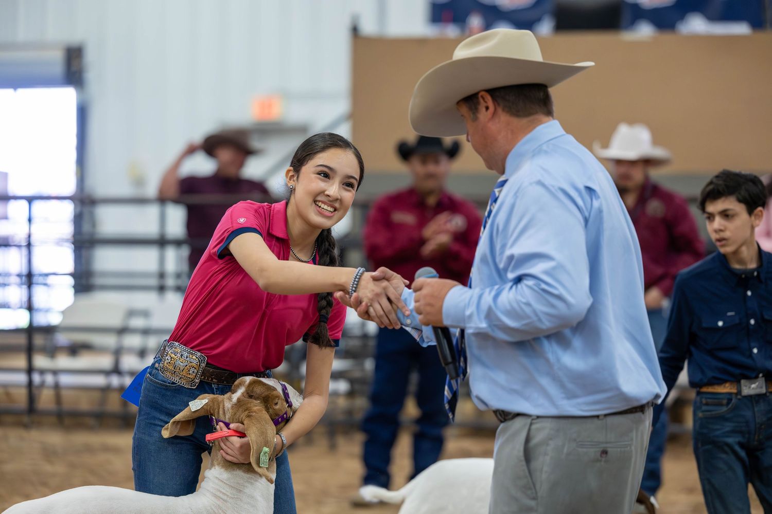A participant shakes hands with a judge during a livestock show competition.