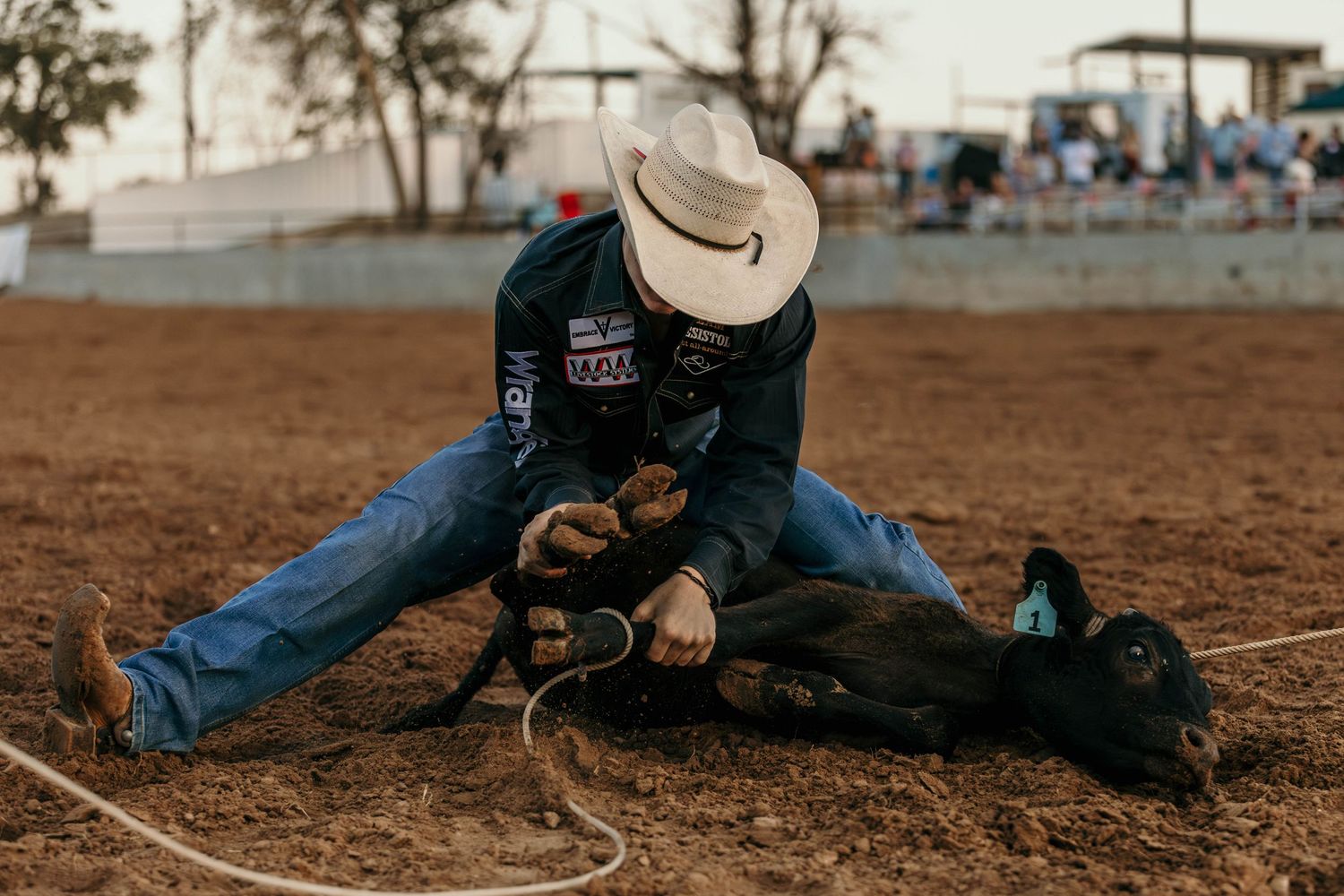 Cowboy performing calf roping technique during rodeo competition.