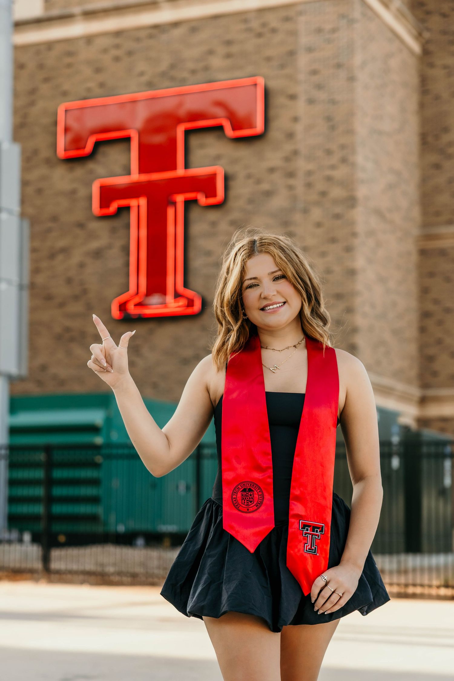 Graduation portraits featuring red Texas Tech stoles and banners on a brick building exterior.
