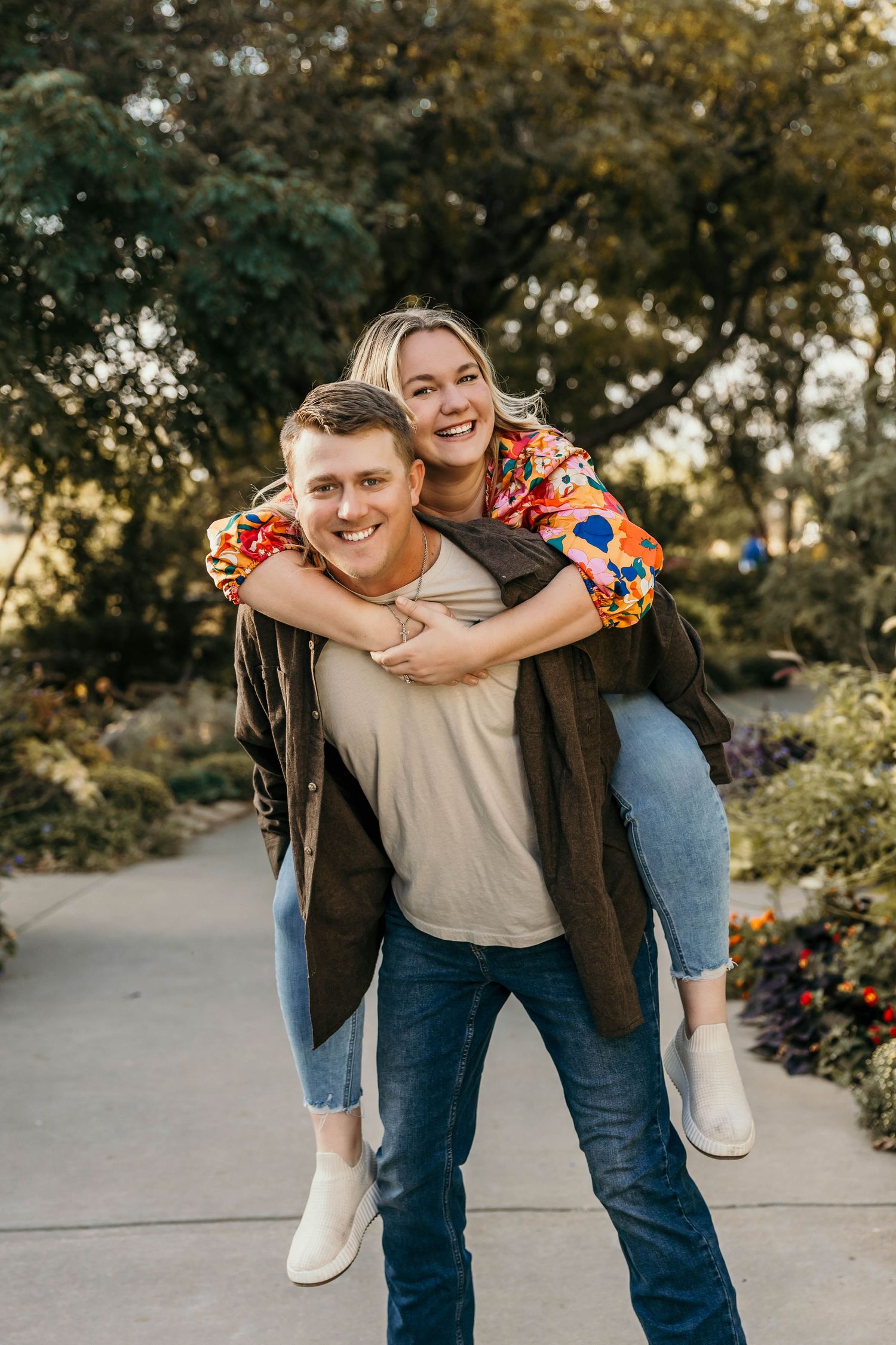 A joyful couples portrait featuring a piggyback ride on a garden path during golden hour.