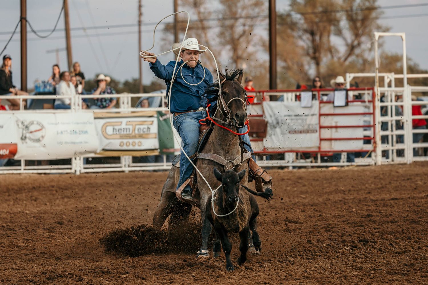 Cowgirl competing in barrel racing event at dusty rodeo arena.
