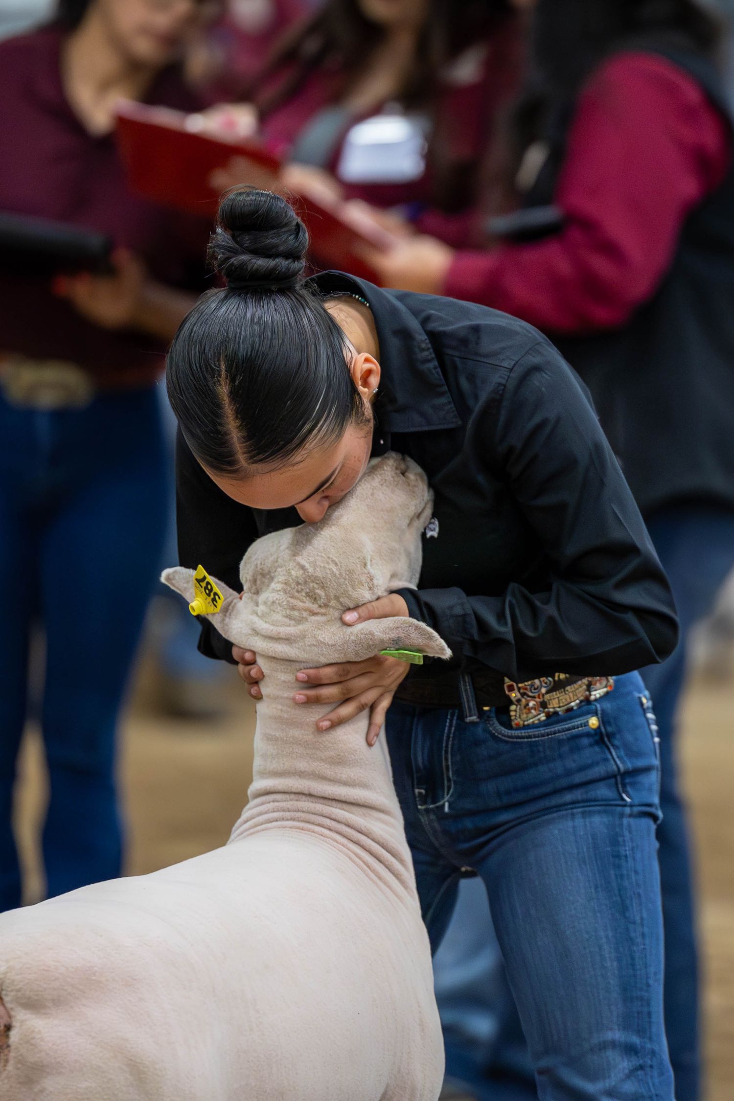 A competitor embraces their show animal during an emotional moment at a livestock competition.