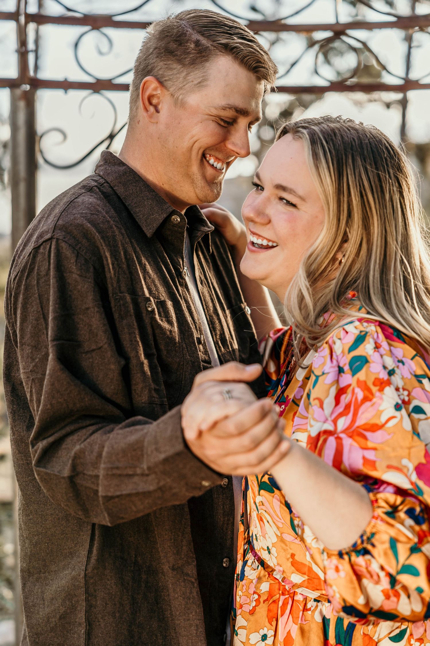 A romantic close-up portrait of a couple sharing an intimate moment under a decorative metal structure.