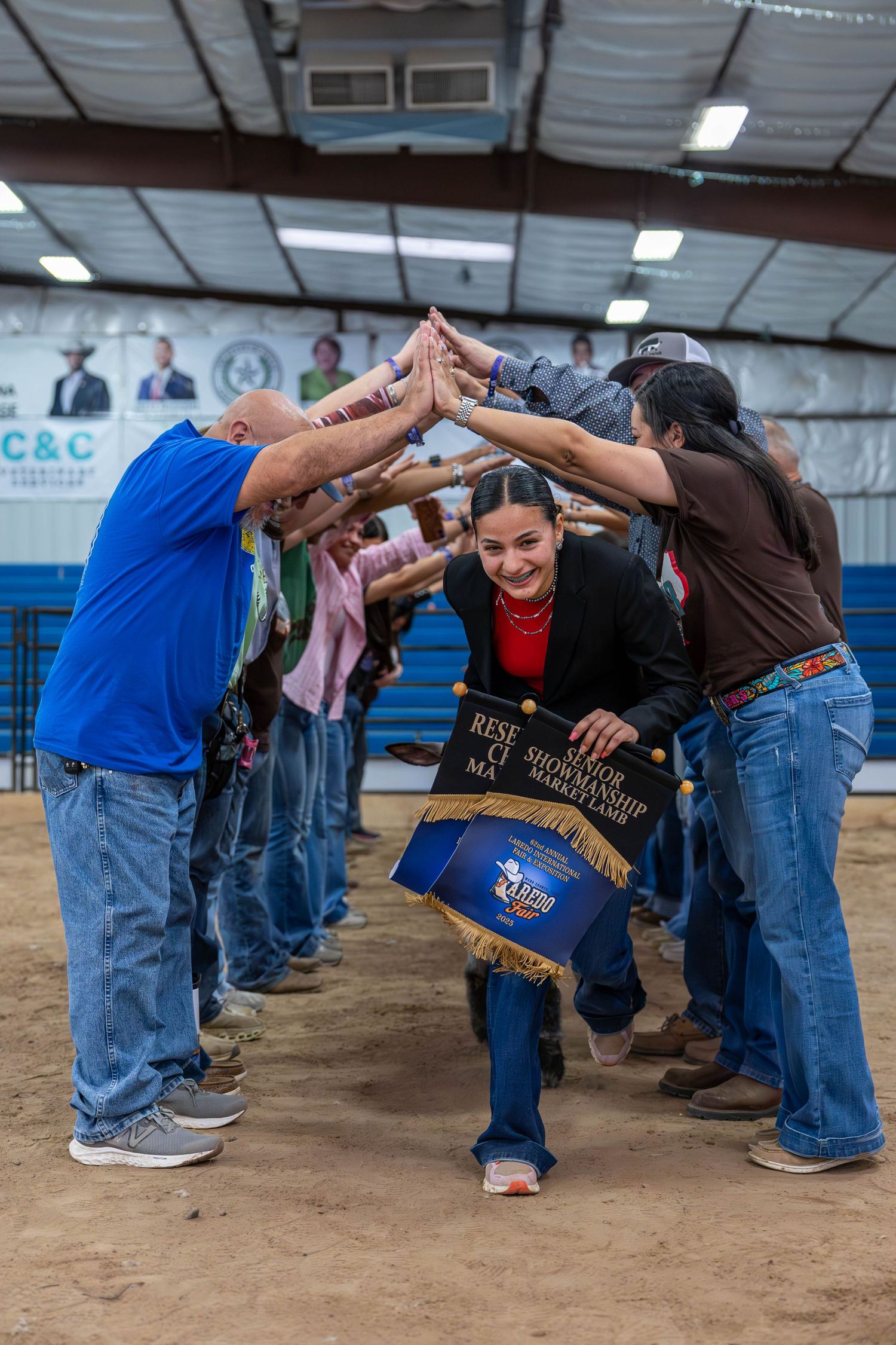 Participants forming a celebratory arch for a winner at a youth livestock show.