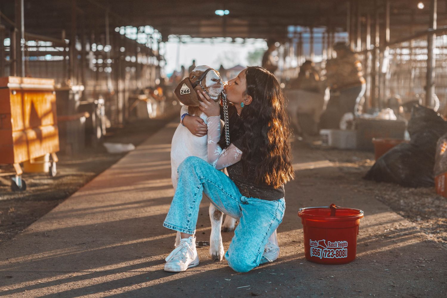 Two people dressed in matching turquoise pants sharing an intimate moment together at a covered outdoor market.