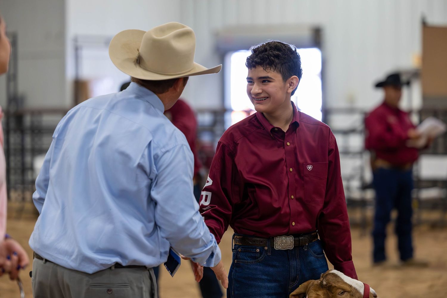 Two participants interact during a livestock show event in an indoor arena.