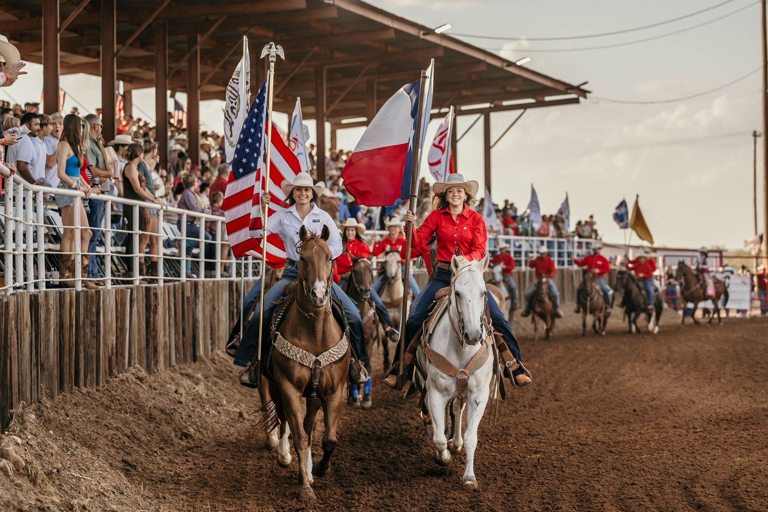Parade riders carrying flags on horseback during rodeo opening ceremony.