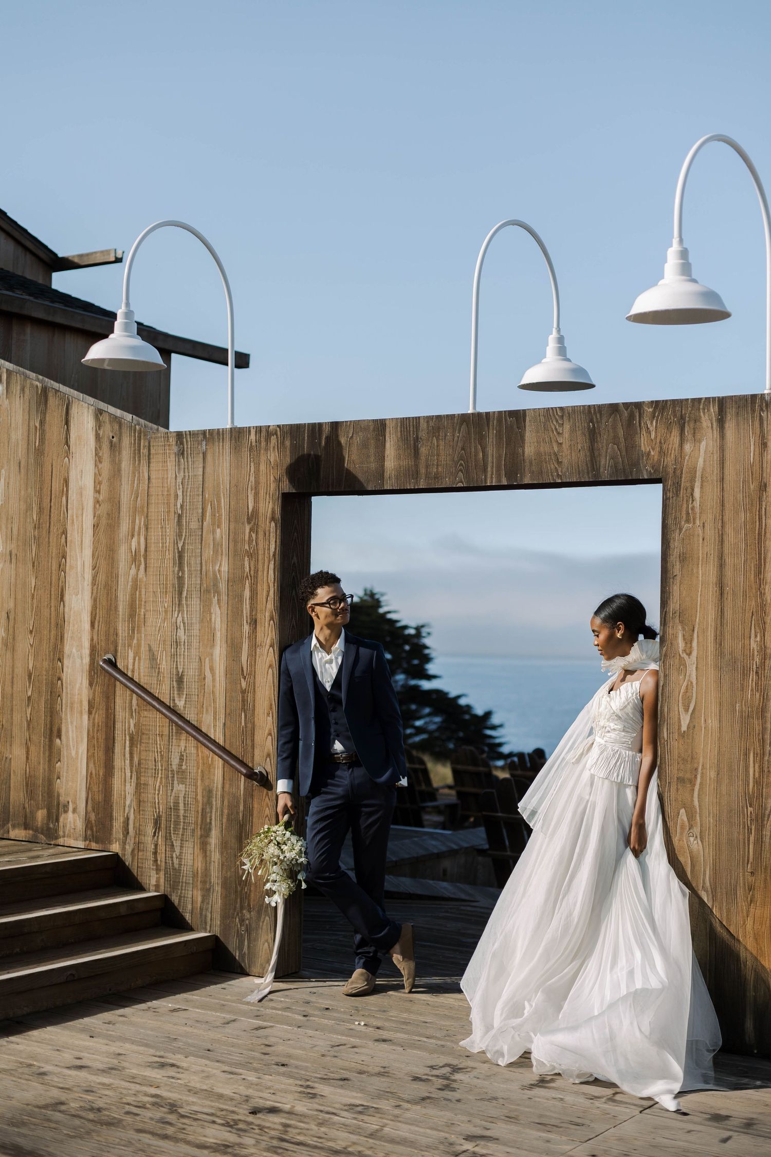 A sequence of playful wedding photos shows a couple interacting behind a wooden fence with pendant lights overhead.