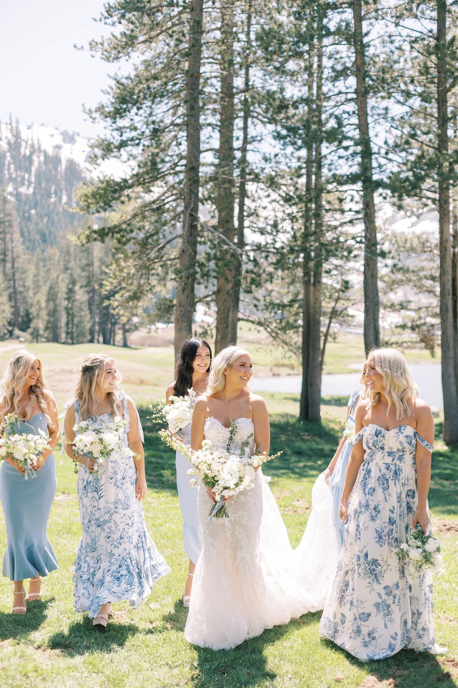 Bridal party in mixed blue dresses gather for photos in a sunny mountain setting at everline resort in lake tahoe.