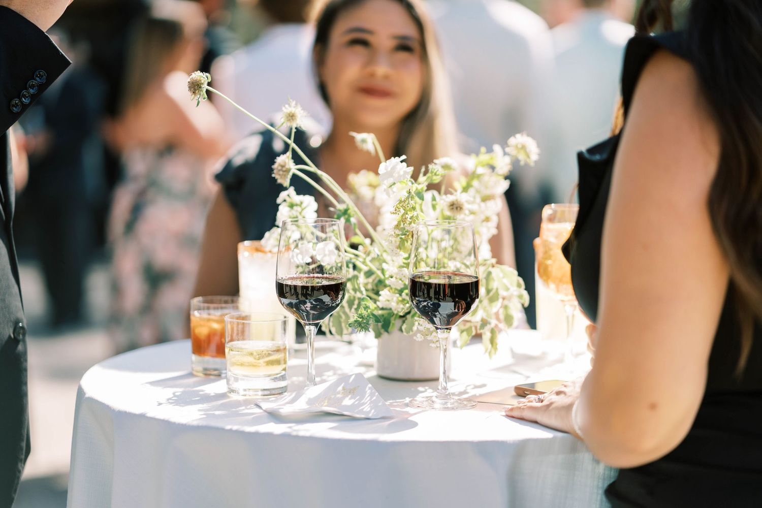 Wedding reception cocktail table with wine glasses and delicate floral centerpiece.
