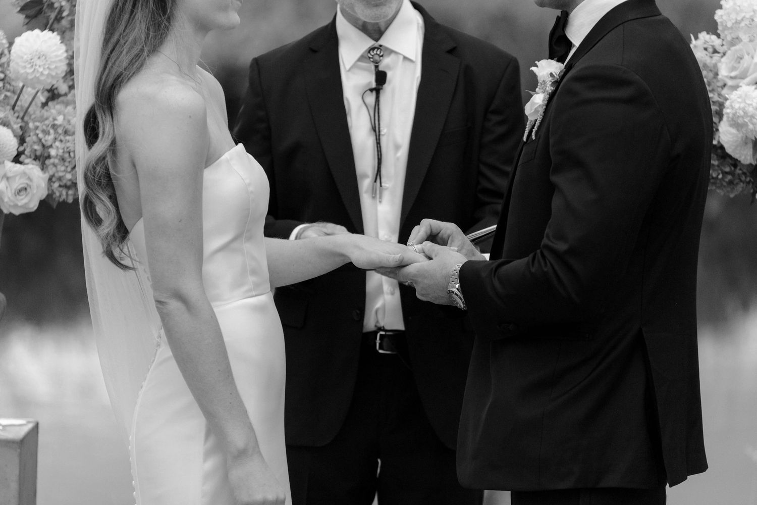 Wedding ceremony group in formal black and white attire outdoors.