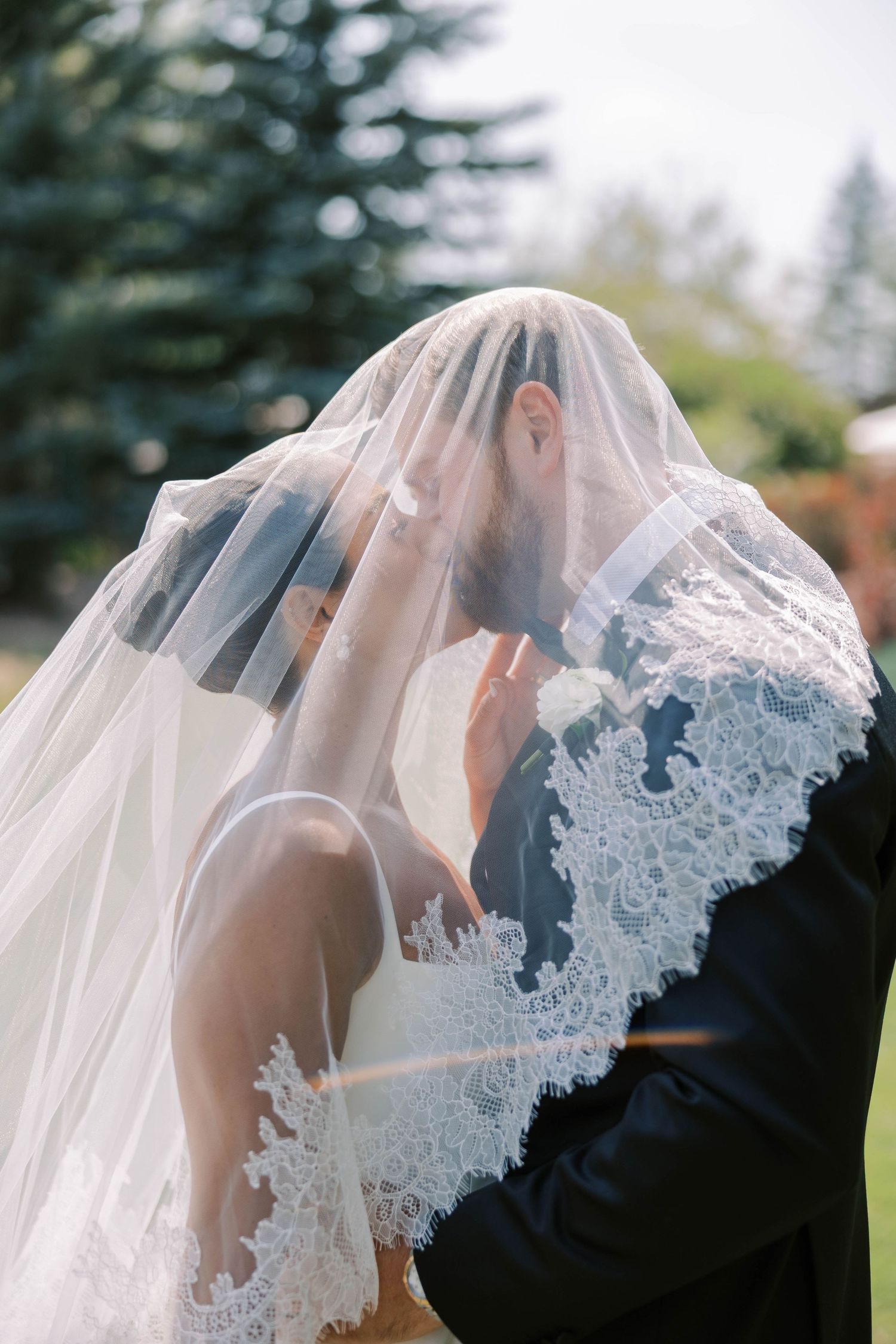 A romantic wedding kiss sequence showing the veil flowing in the breeze as the couple embraces outdoors.