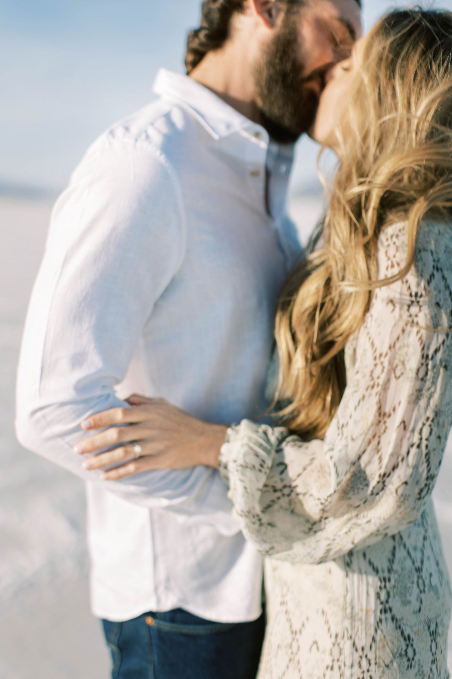 Intimate close-up of couple sharing a romantic kiss against bright natural backdrop.