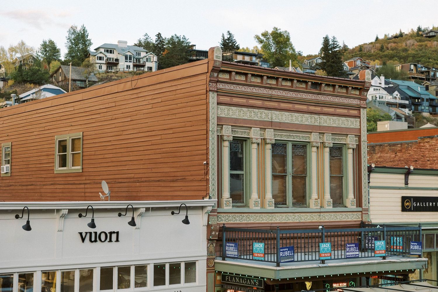 Brown wooden exterior of a modern apartment complex with multiple units and balconies along a hillside.