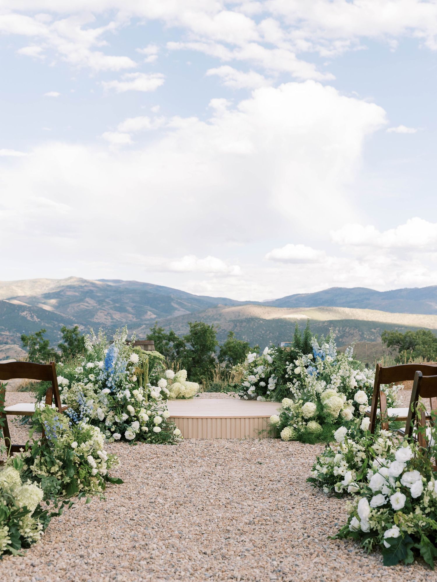 Elegant white floral arrangements decorating outdoor mountain wedding venue.