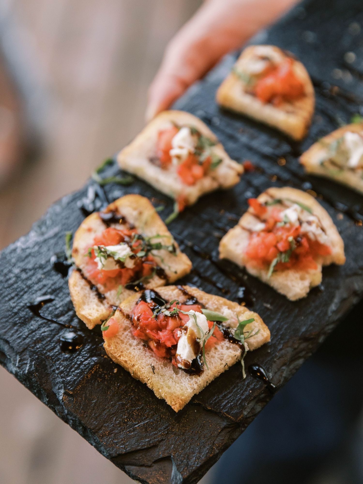 Appetizers with salmon and herbs served on a dark slate board at an upscale event.