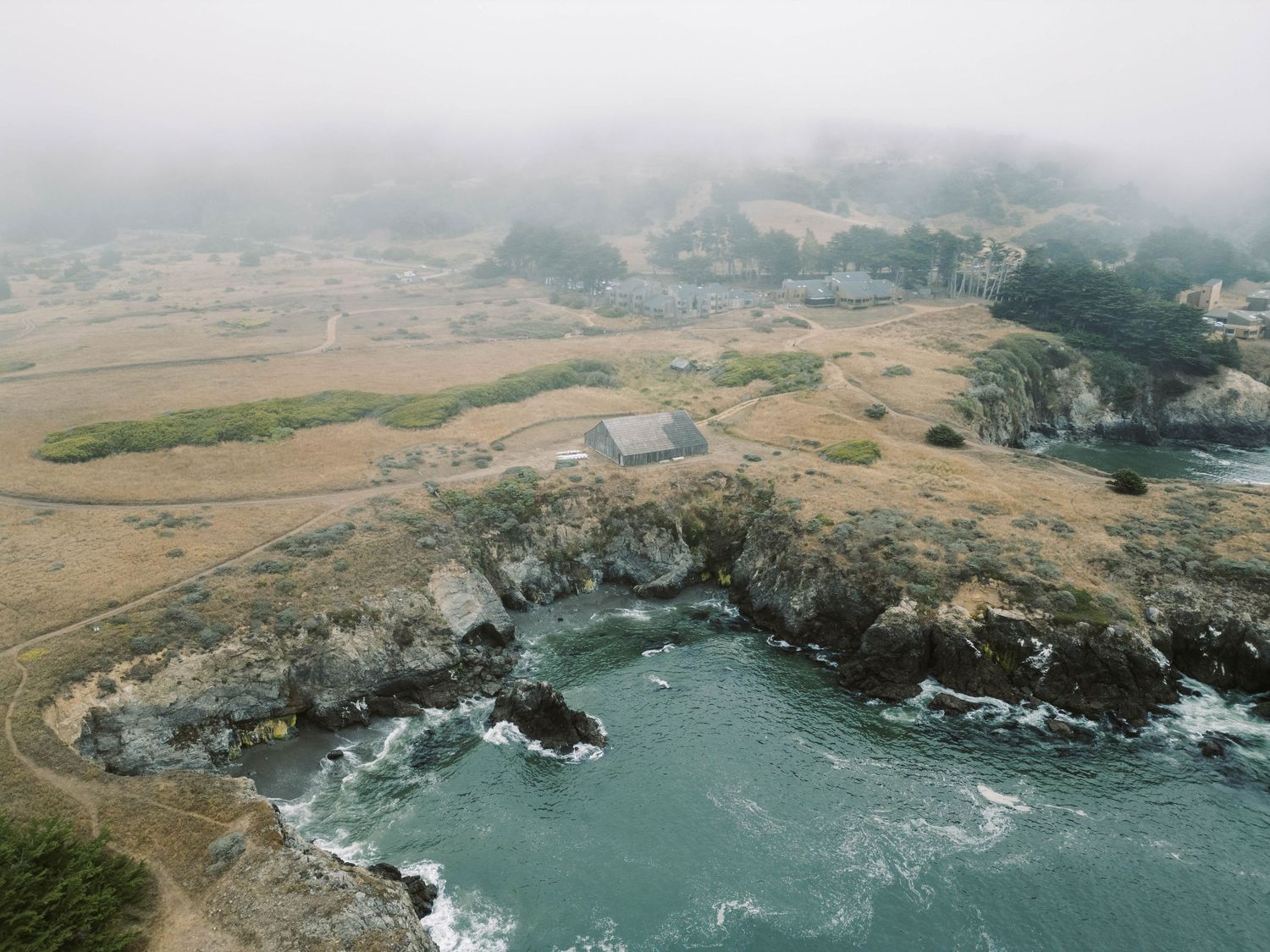 Aerial view of rugged coastal cliffs meeting turquoise ocean waters along a dramatic rocky shoreline.