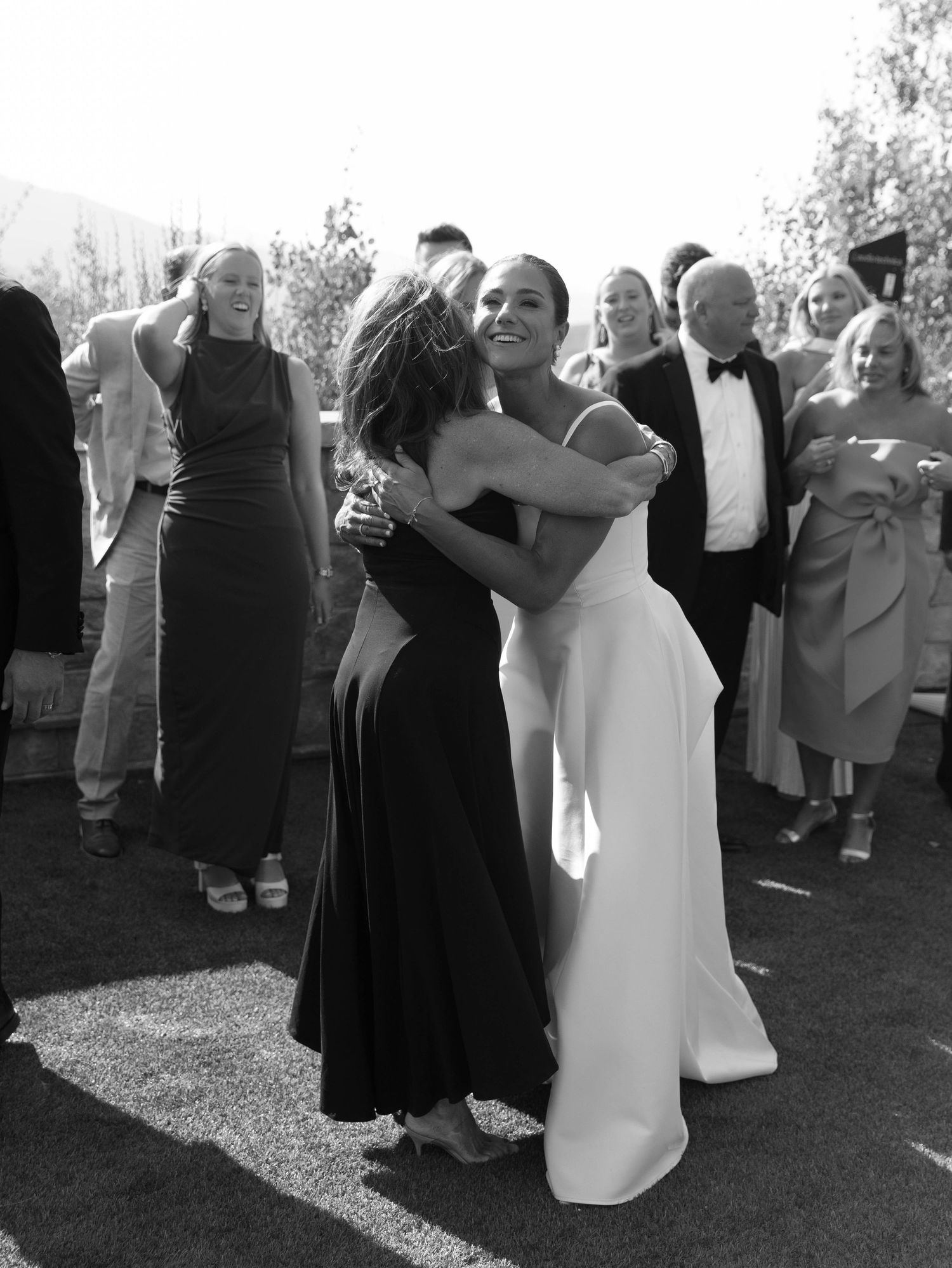 Black and white photo of wedding guests mingling at outdoor reception.