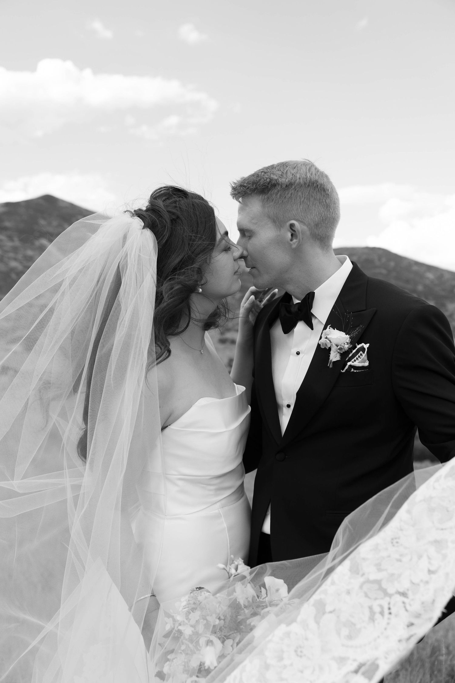 Romantic wedding portraits captured against a mountain backdrop with flowing white veil.
