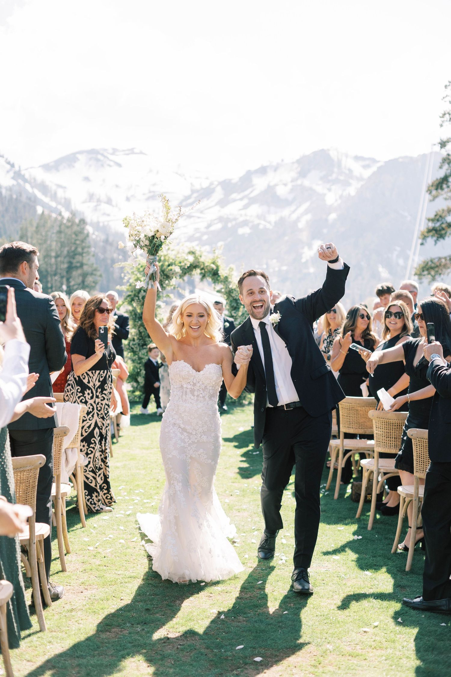 Newlyweds celebrate while walking down aisle with mountain views.
